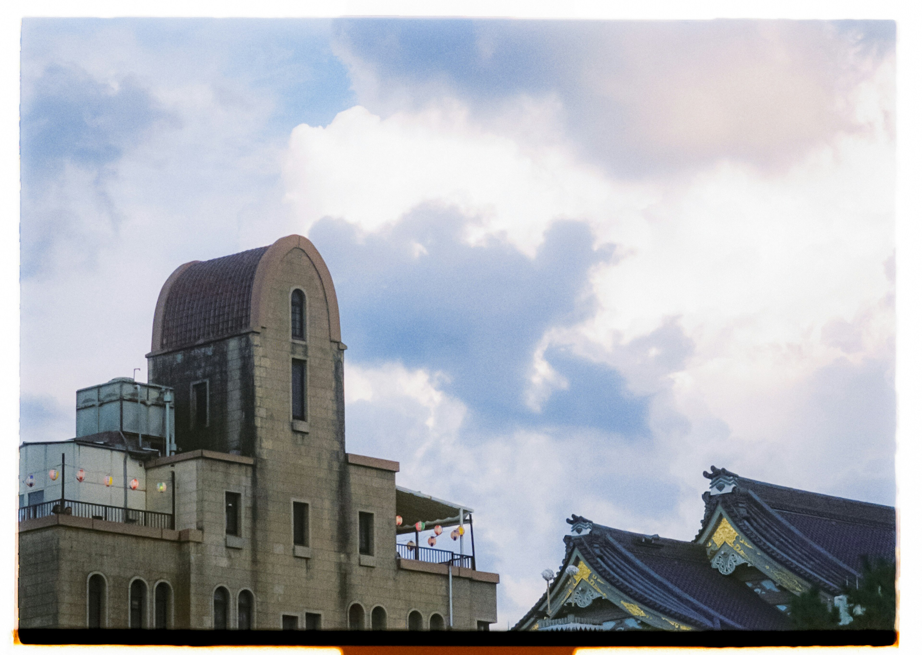 Building rooftop with a curved design against a backdrop of blue sky and clouds