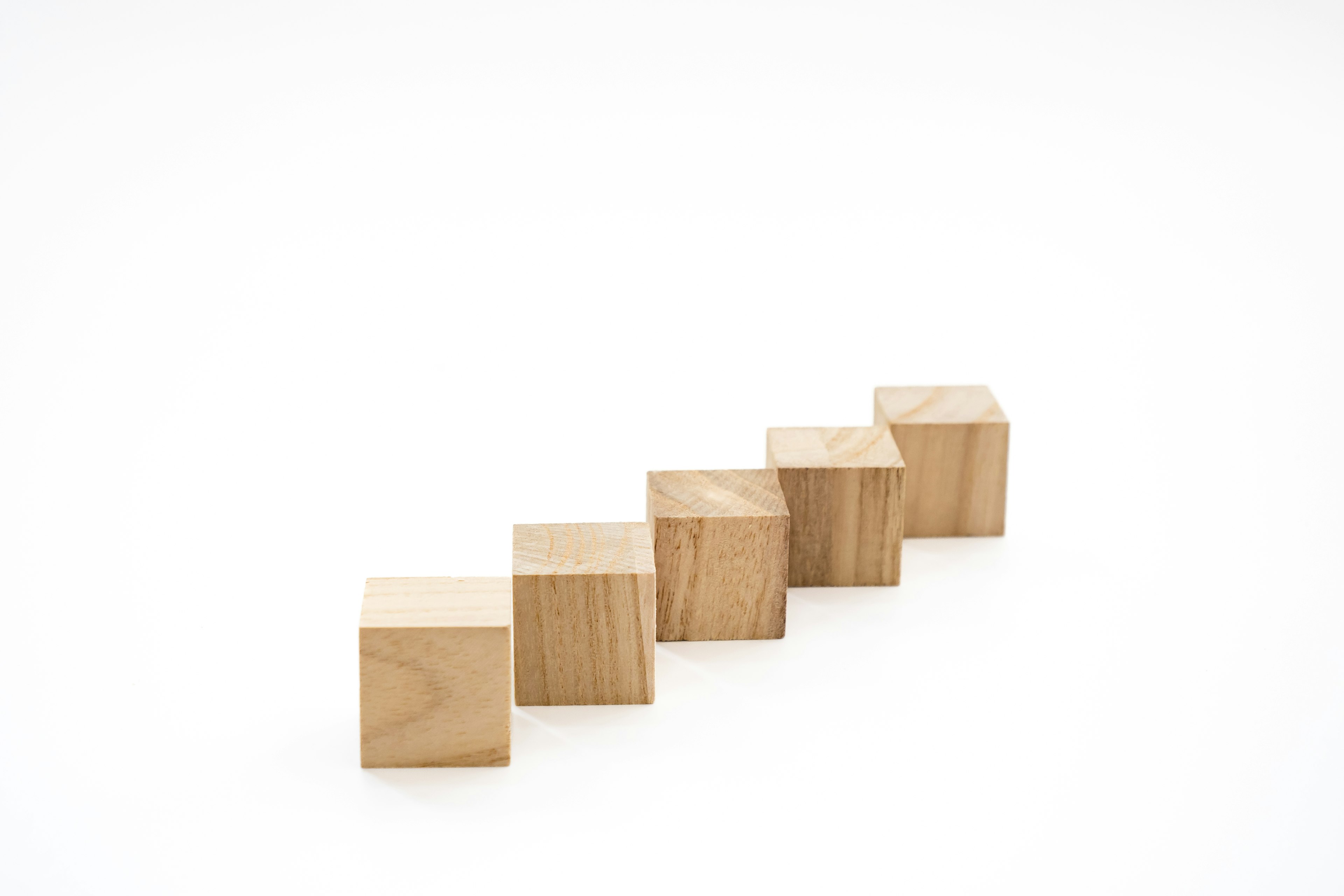 Five wooden cubes arranged in a linear sequence on a white background