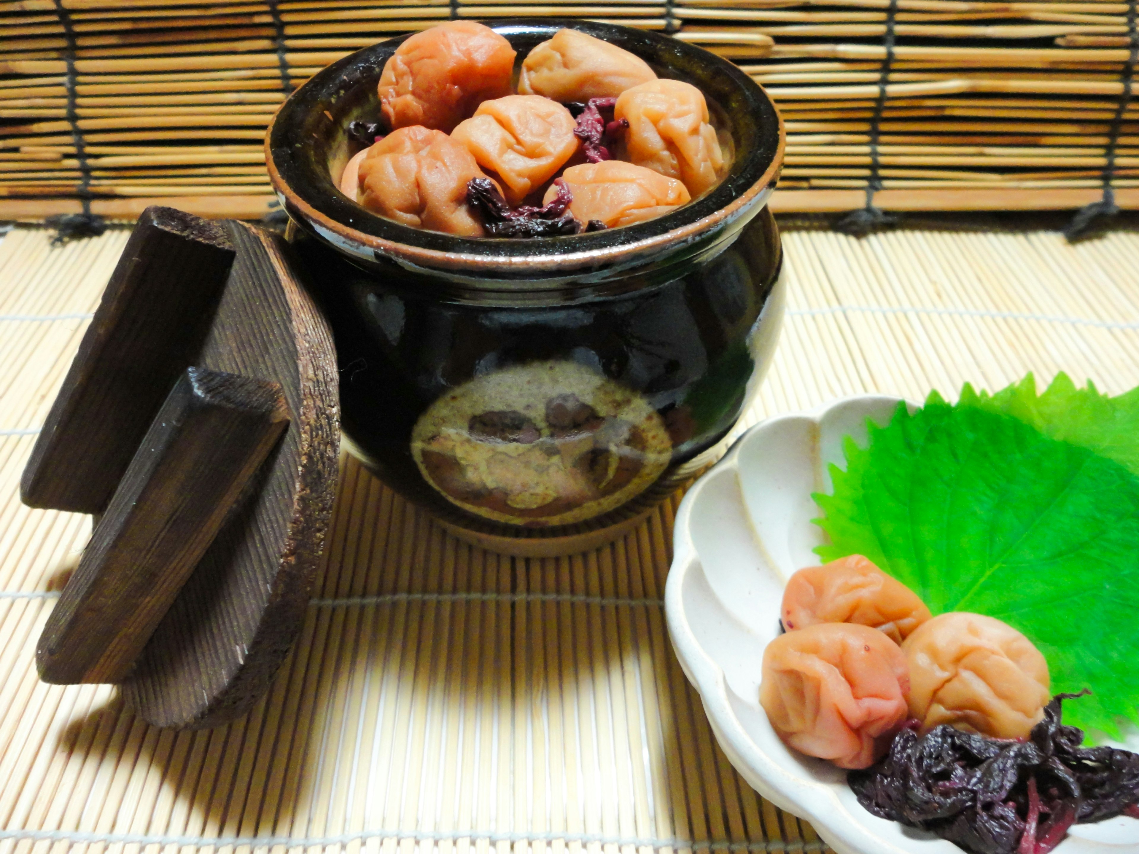 A black ceramic jar filled with pickled plums and shiso leaves