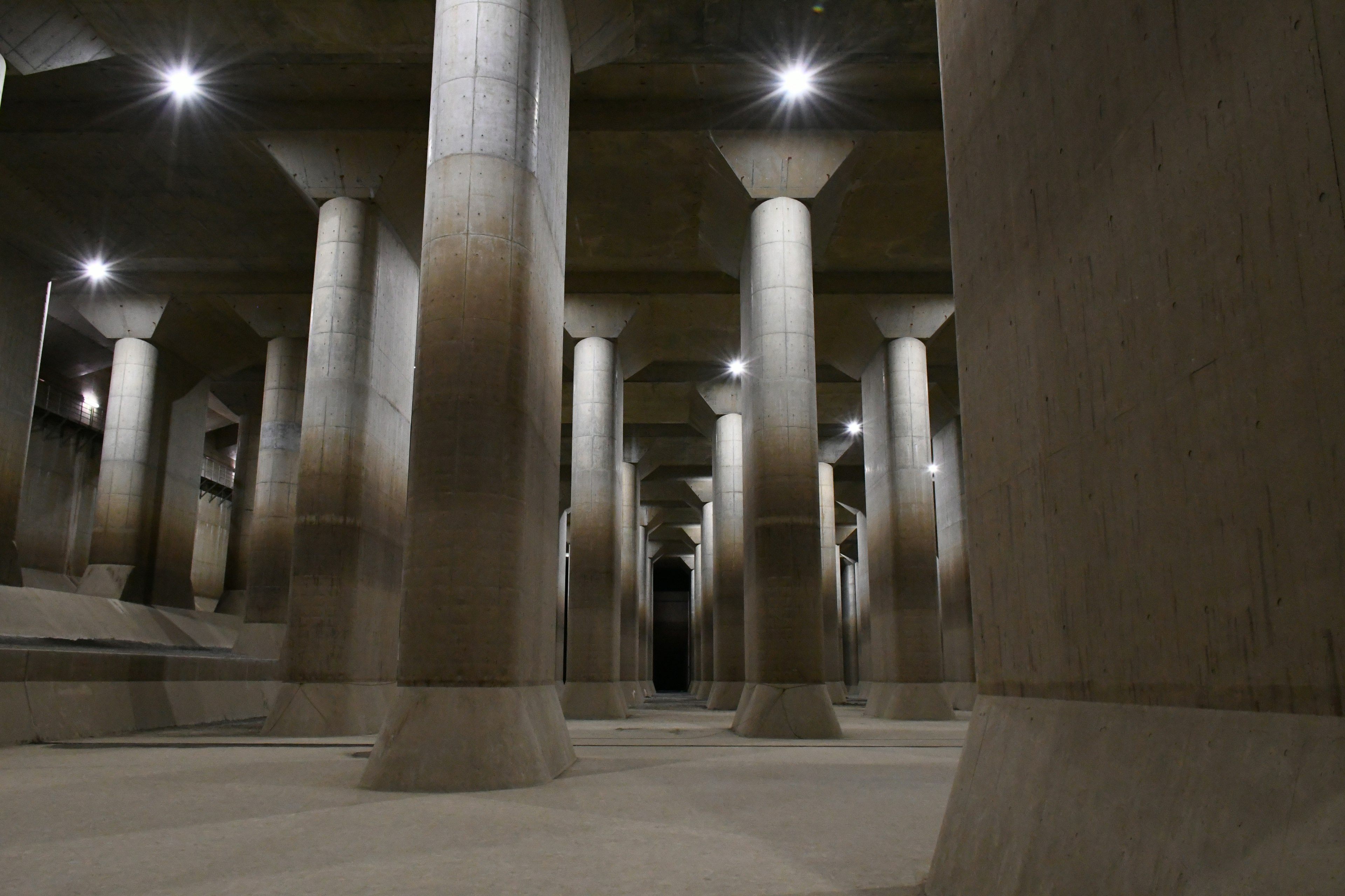 Espace souterrain avec de grandes colonnes en béton et un éclairage distinctif