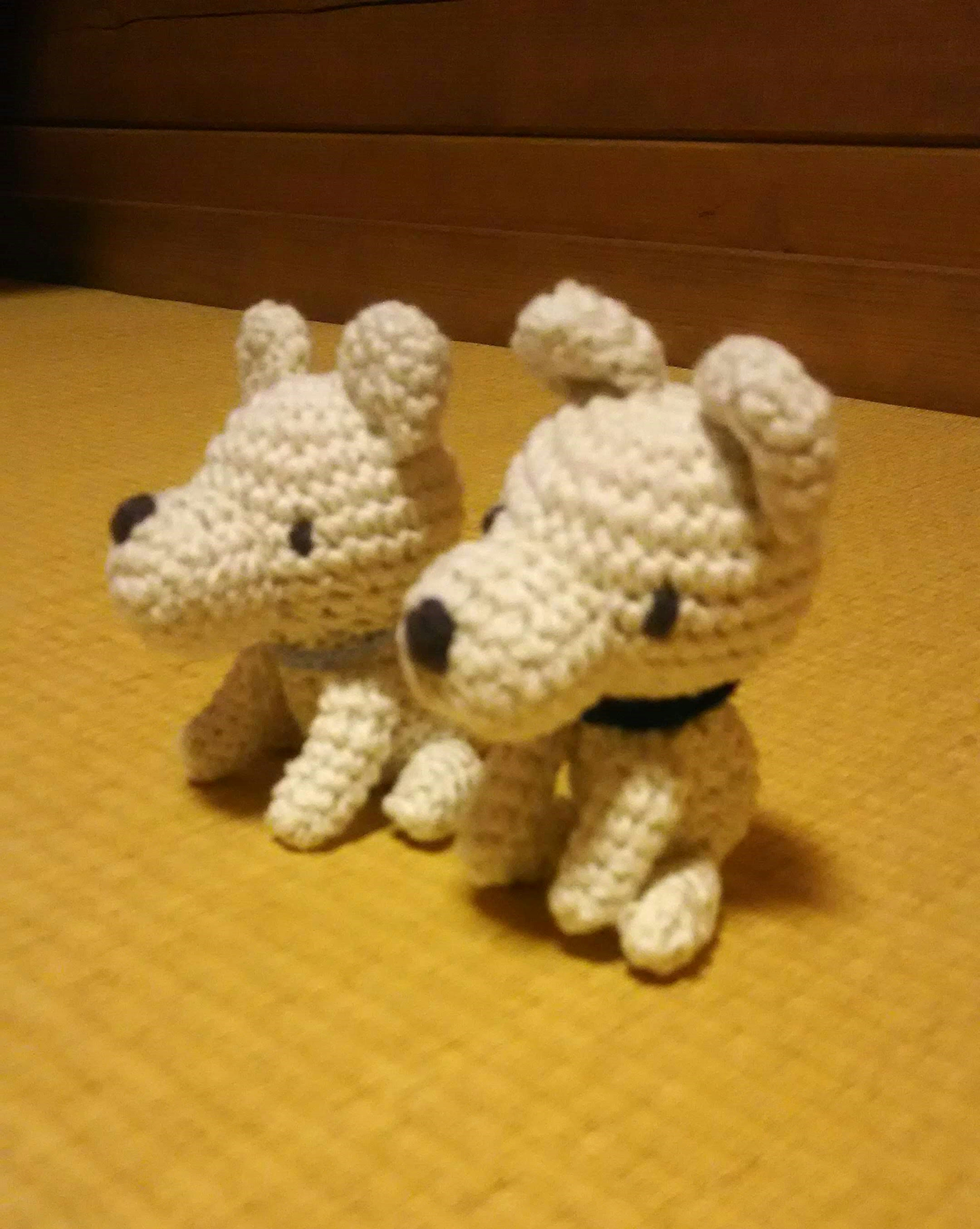 Two white crocheted dogs sitting side by side