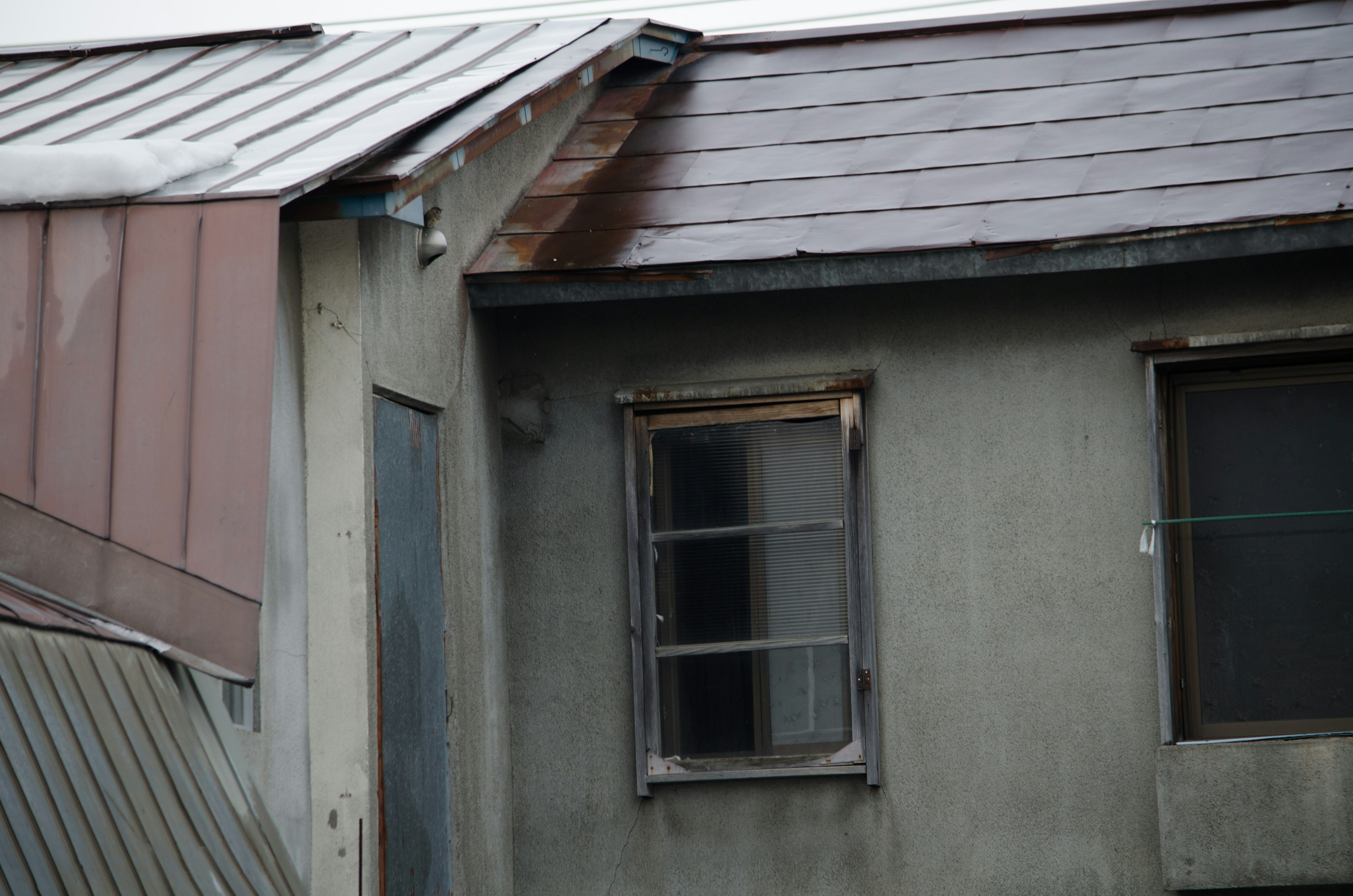 Part of an old building featuring a rusty roof and window