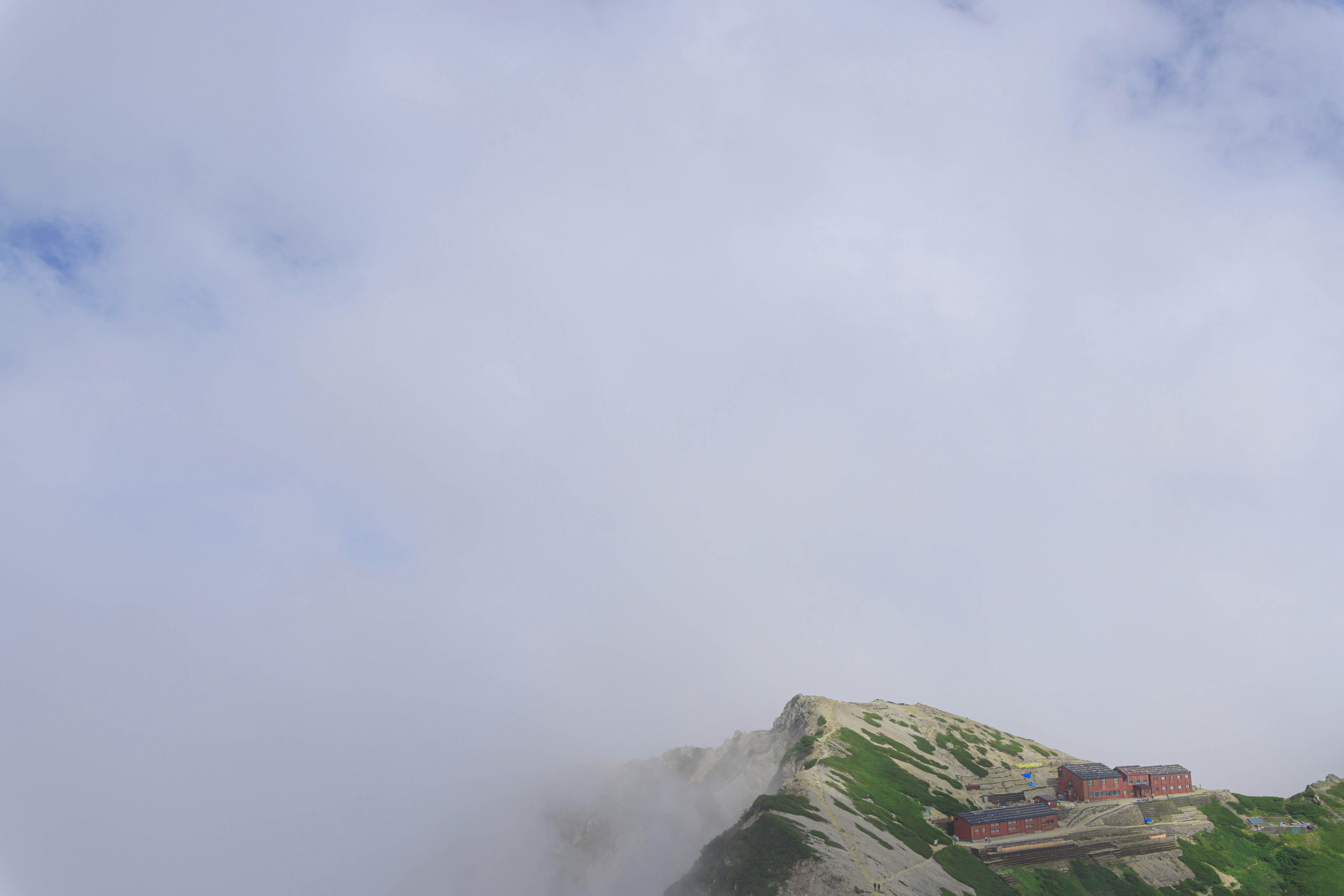 A red building on the peak of a mountain shrouded in mist