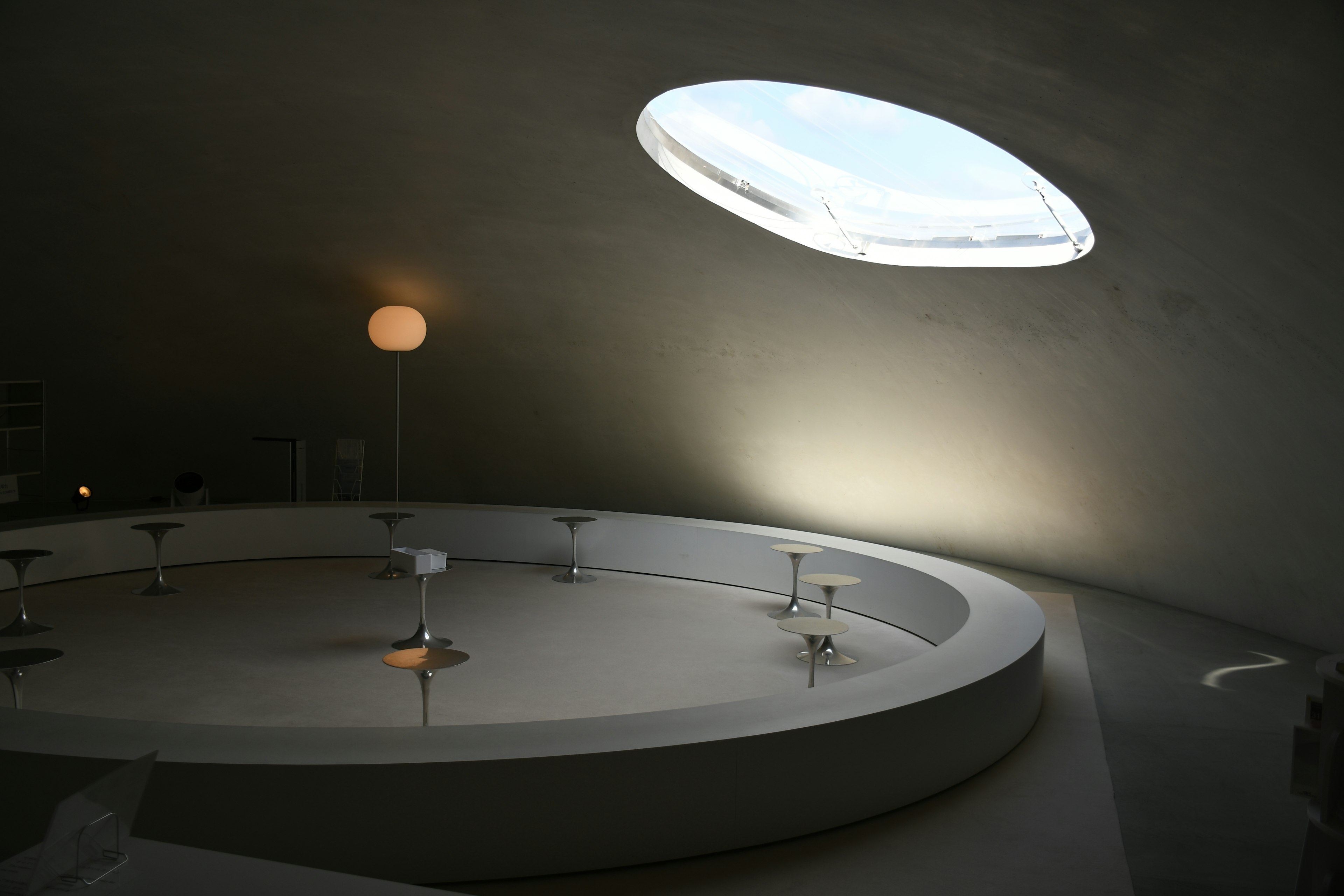 Modern interior featuring a circular white table and chairs with natural light coming through a skylight