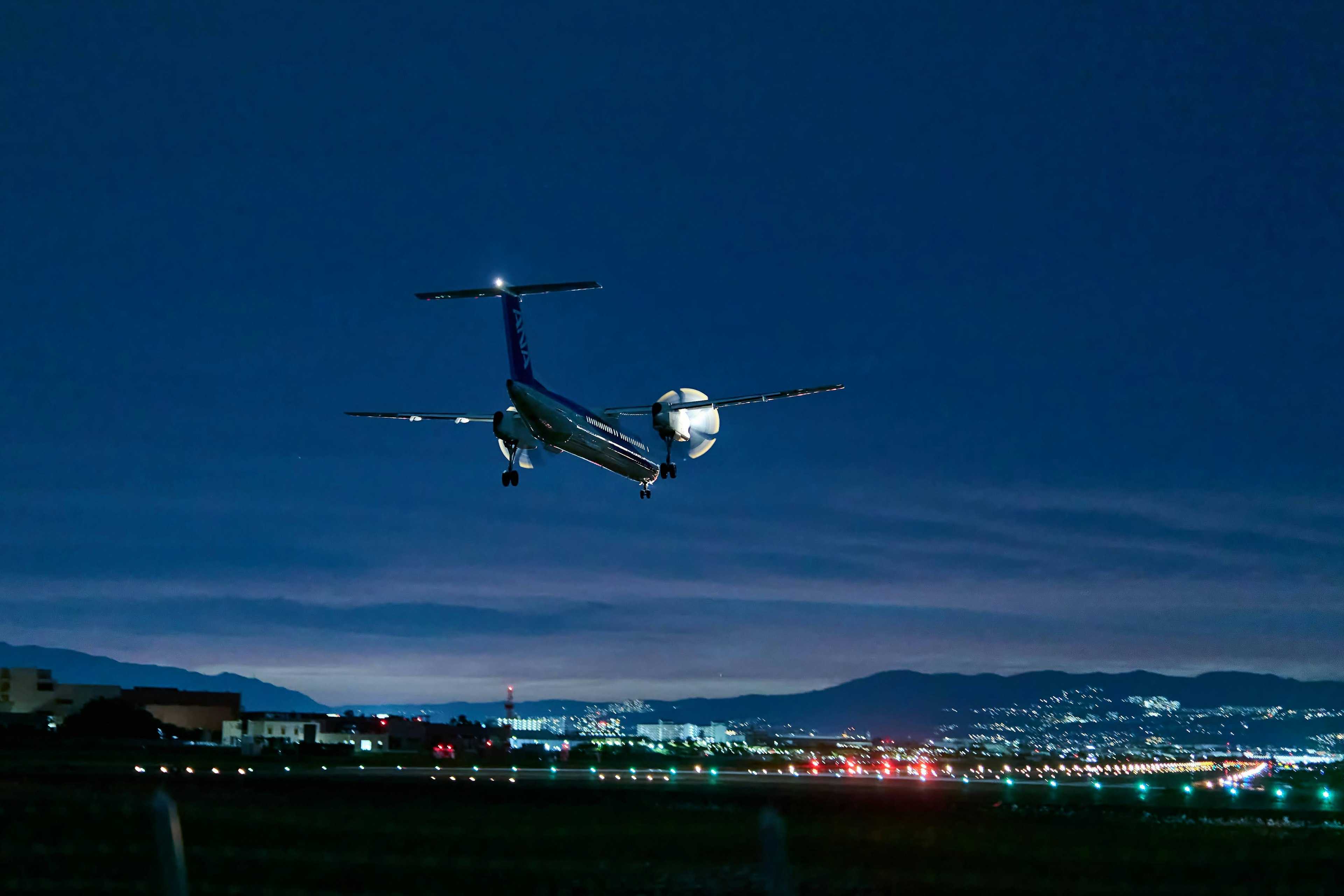 Airplane flying at night with city lights in the background