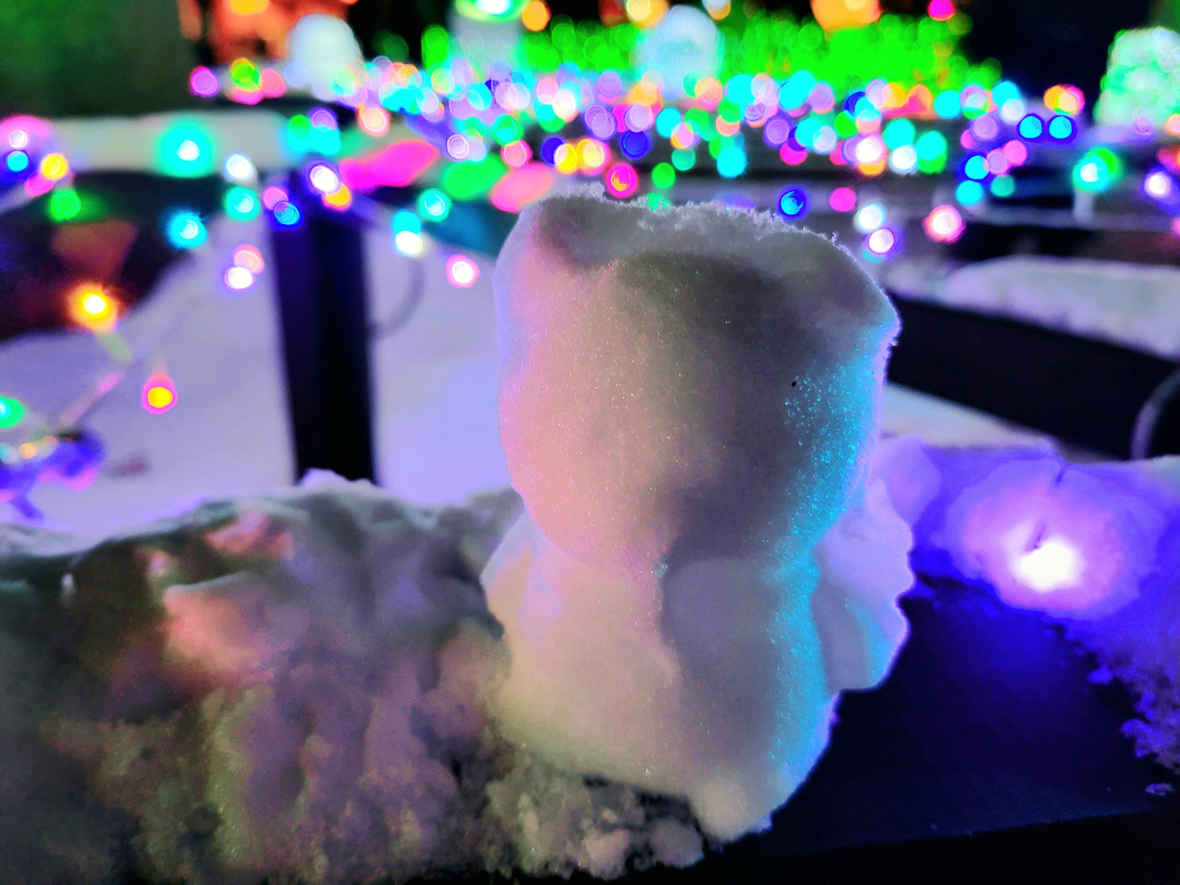 Snow figure with colorful lights in the background