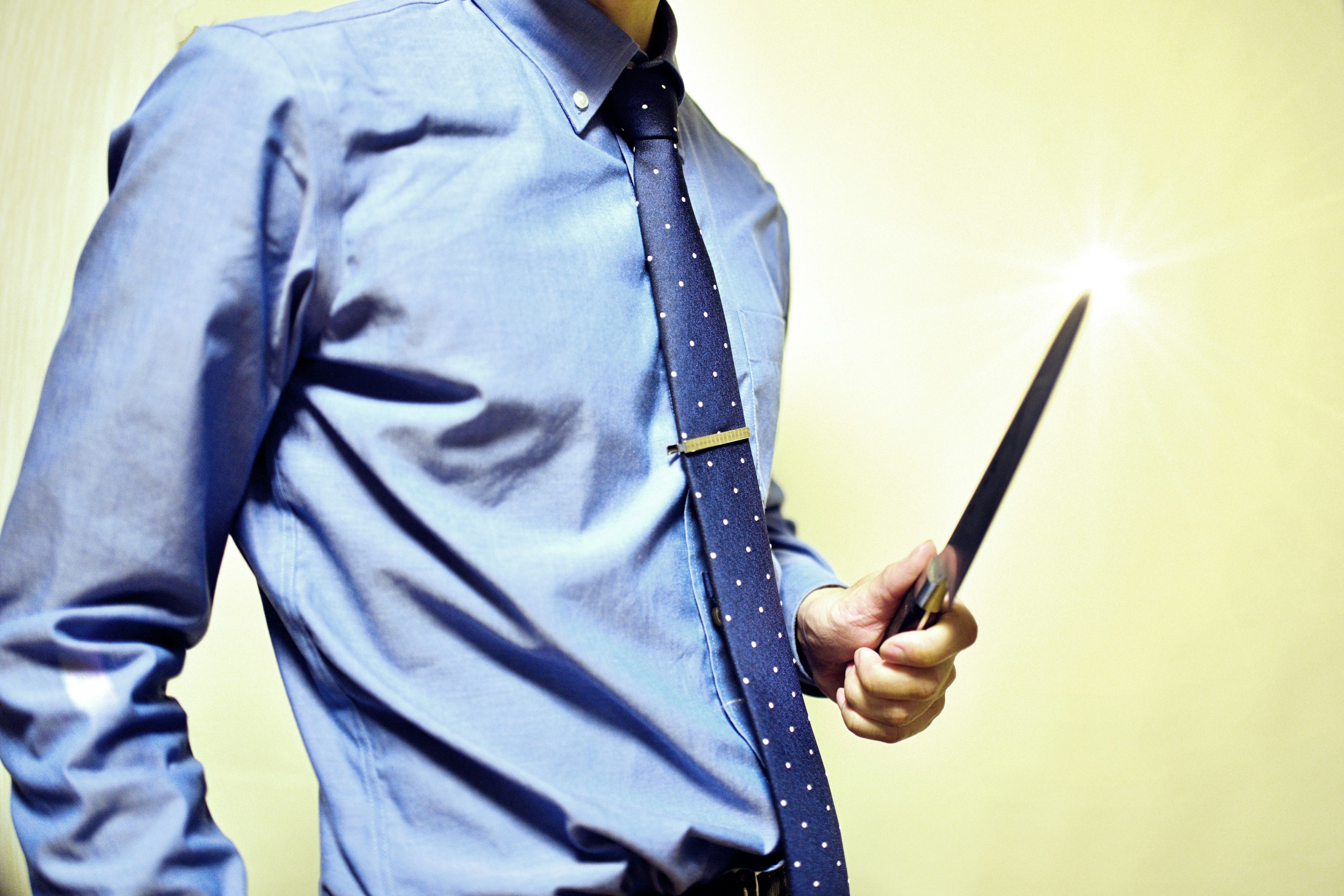 A man in a blue shirt holding a shiny pen