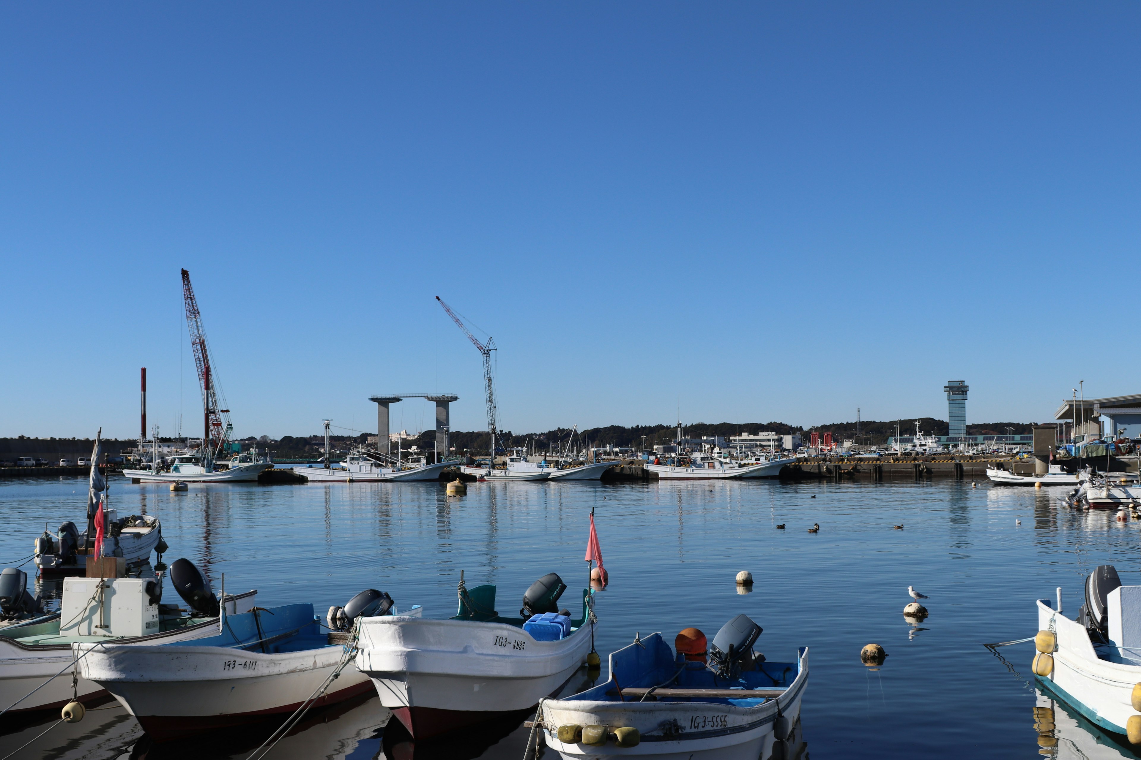 Small boats docked in a quiet harbor under a clear blue sky