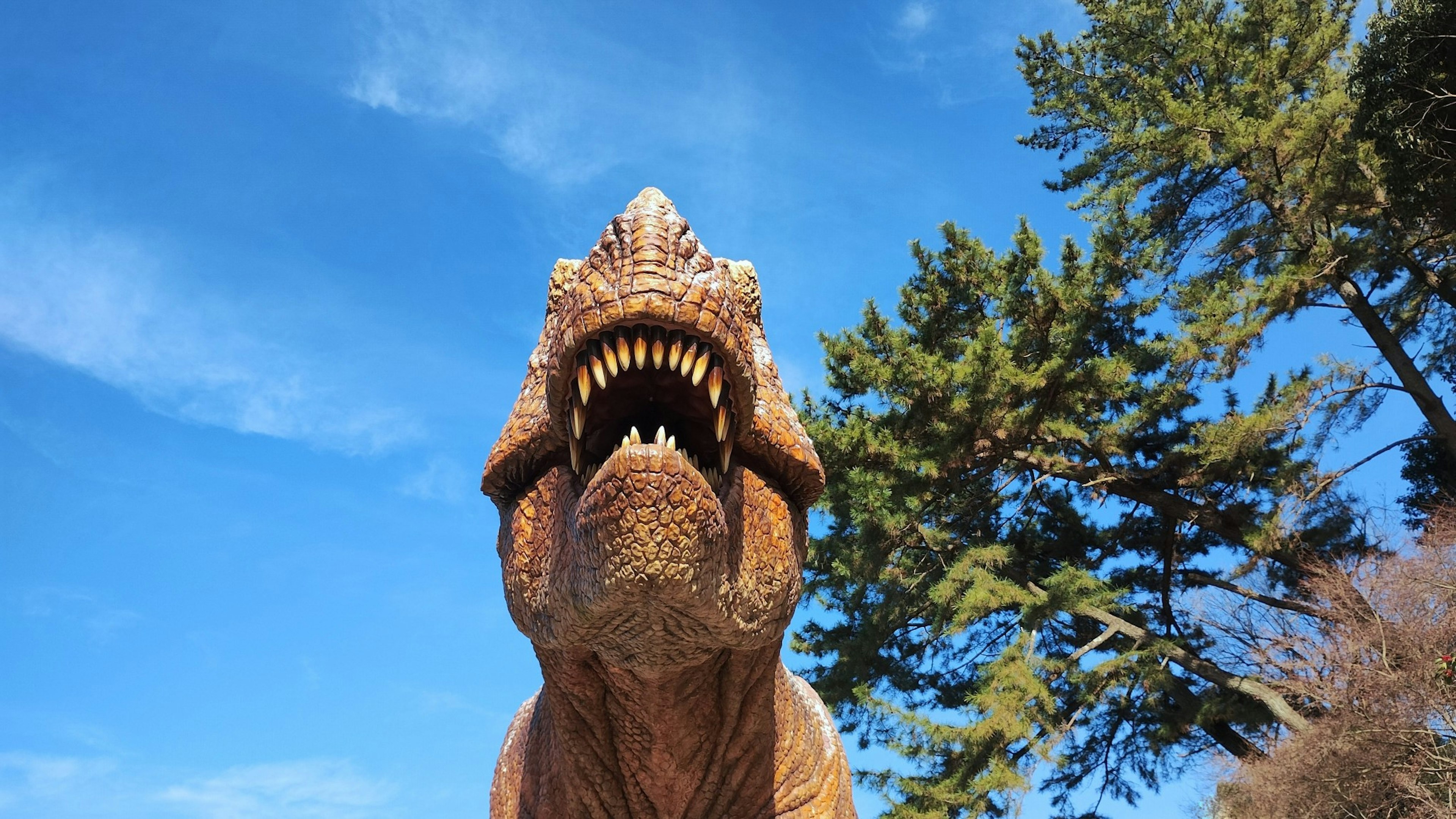 Modelo de dinosaurio rugiendo bajo un cielo azul