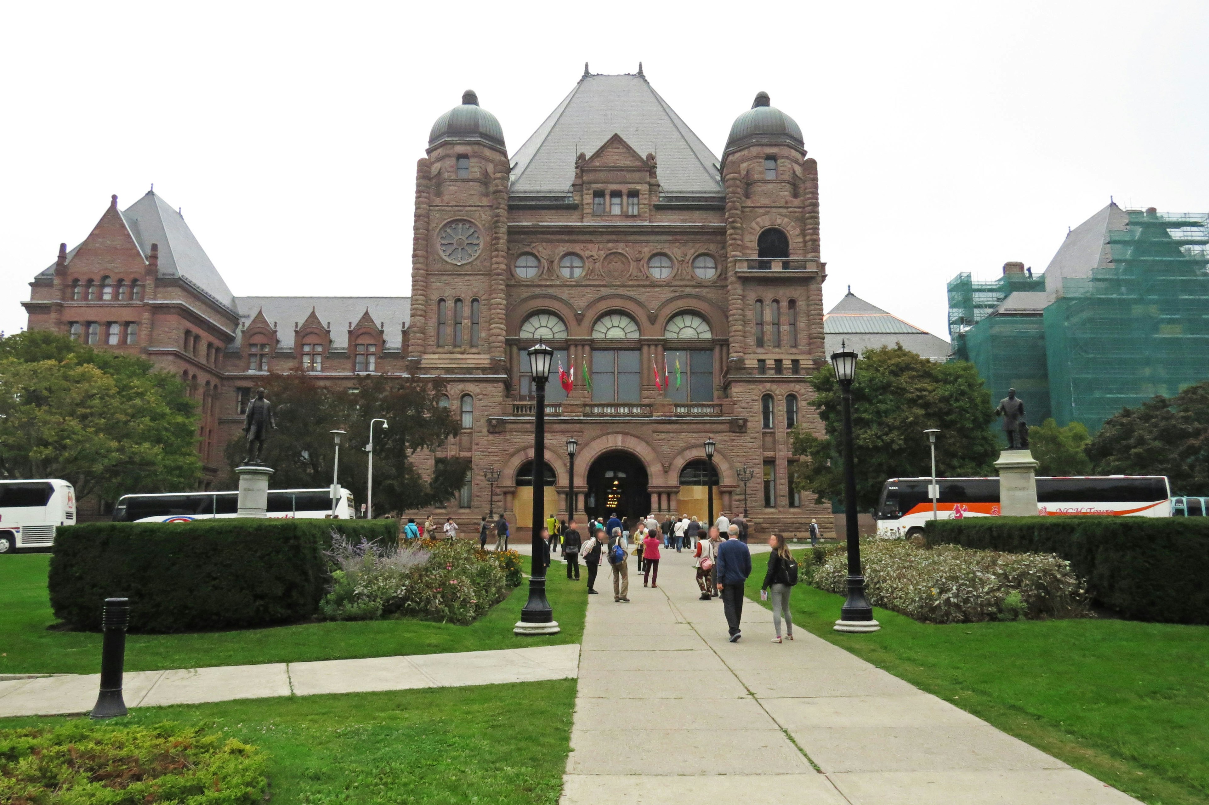 Historic building with a lush garden and people walking