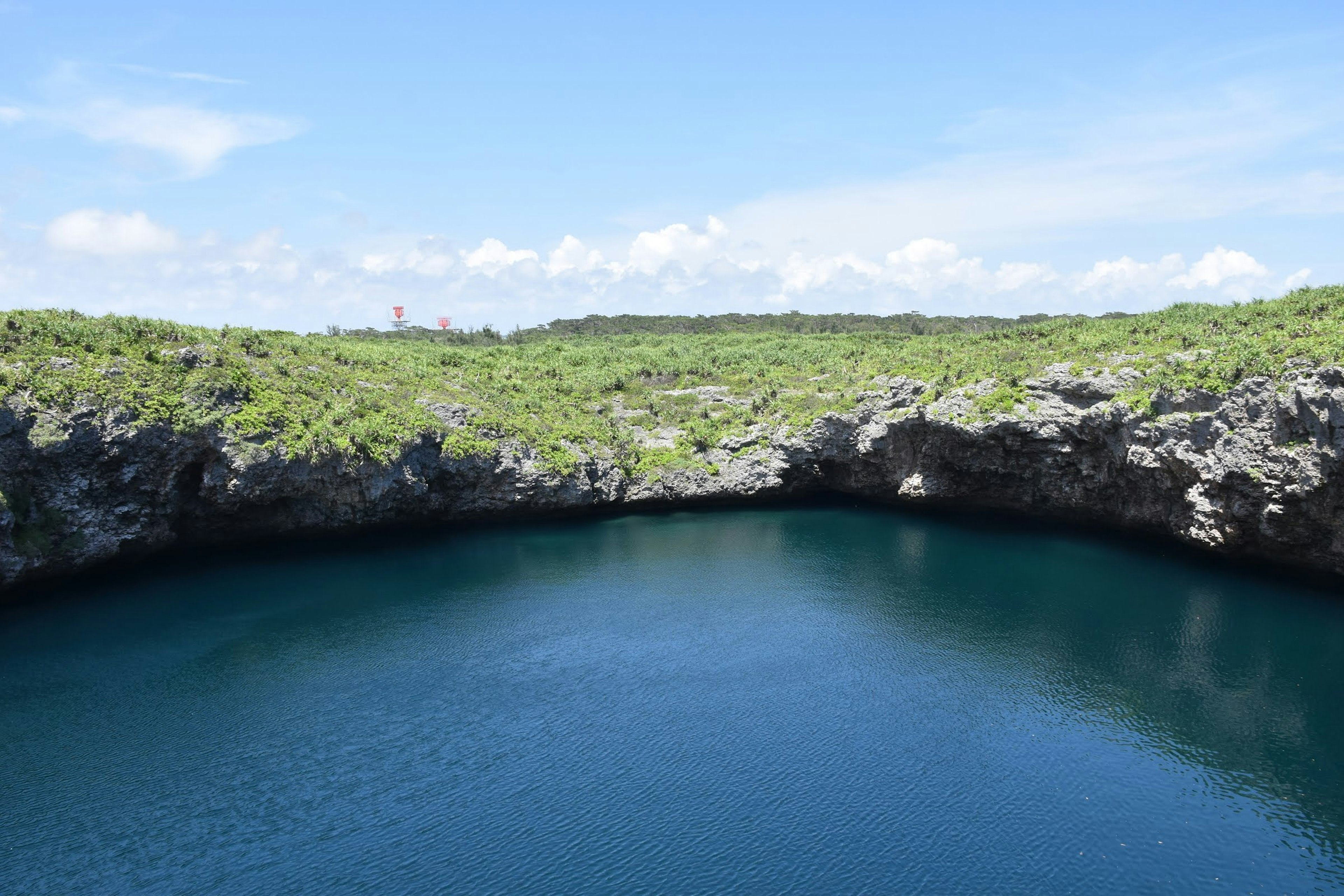 Lago de cráter con agua azul rodeado de colinas verdes