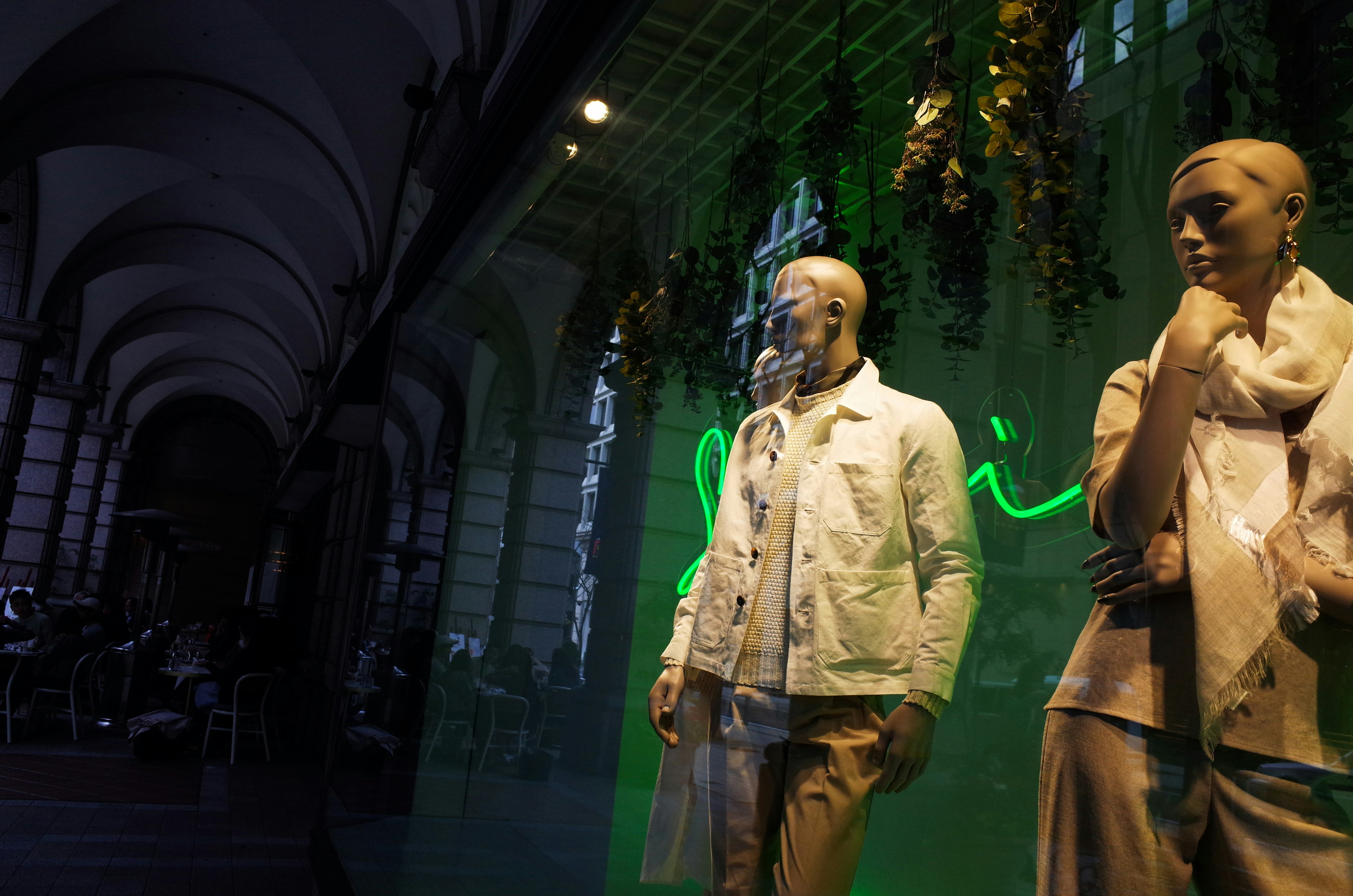 Fashion display featuring mannequins in white jacket and beige pants with green neon sign