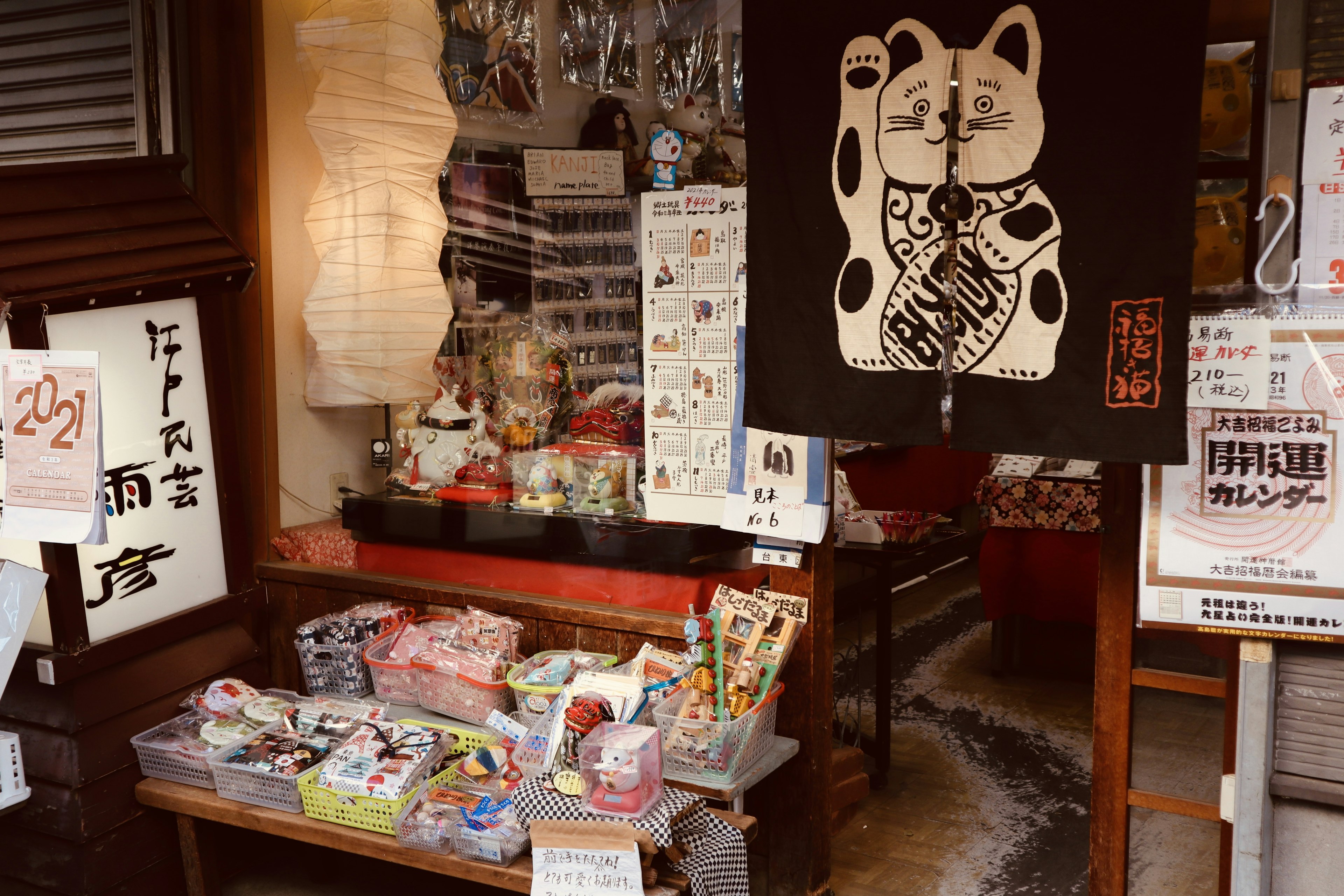 Traditional Japanese shop entrance featuring a lucky cat painting with various products displayed