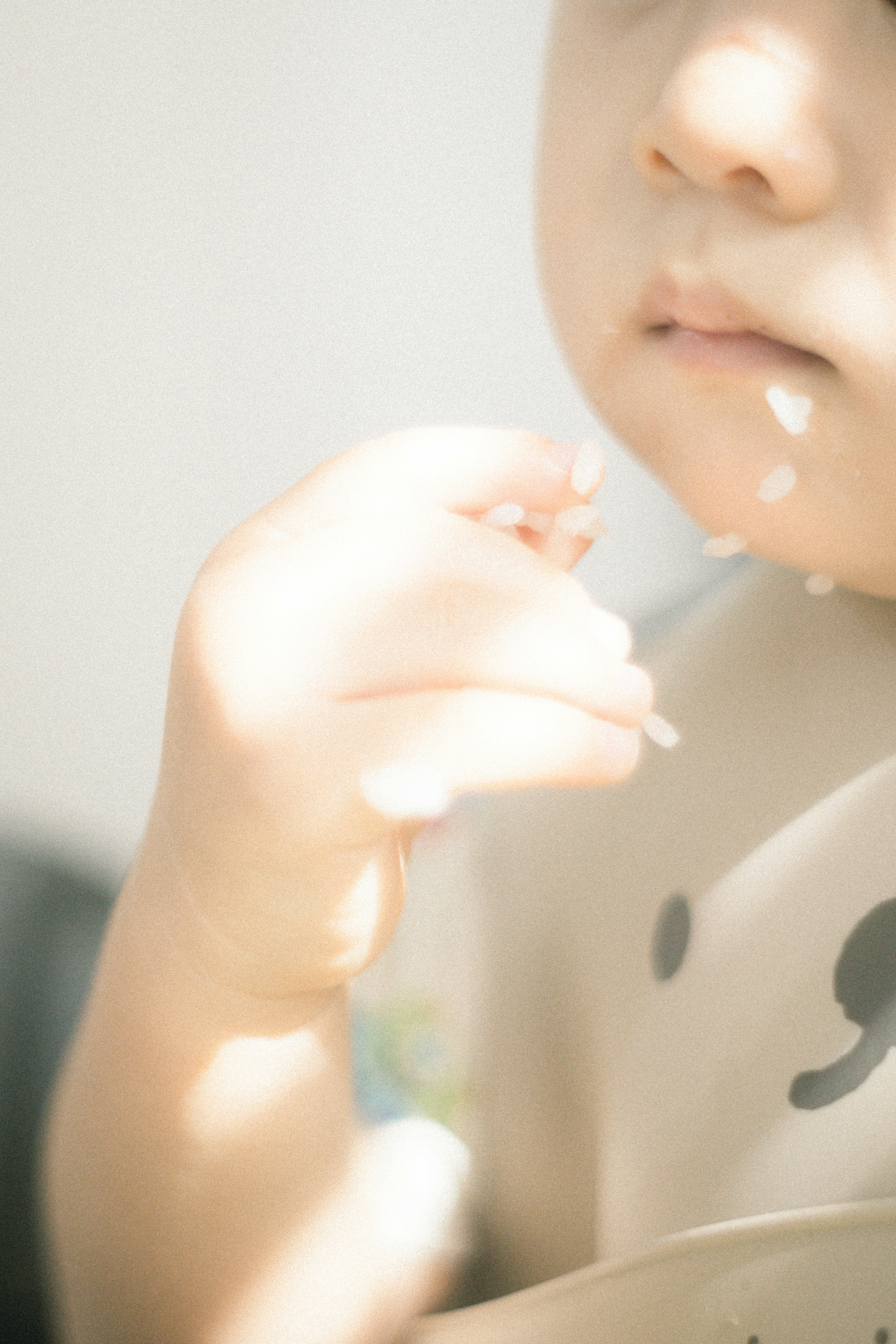 Close-up wajah dan tangan bayi dengan jari dekat mulut