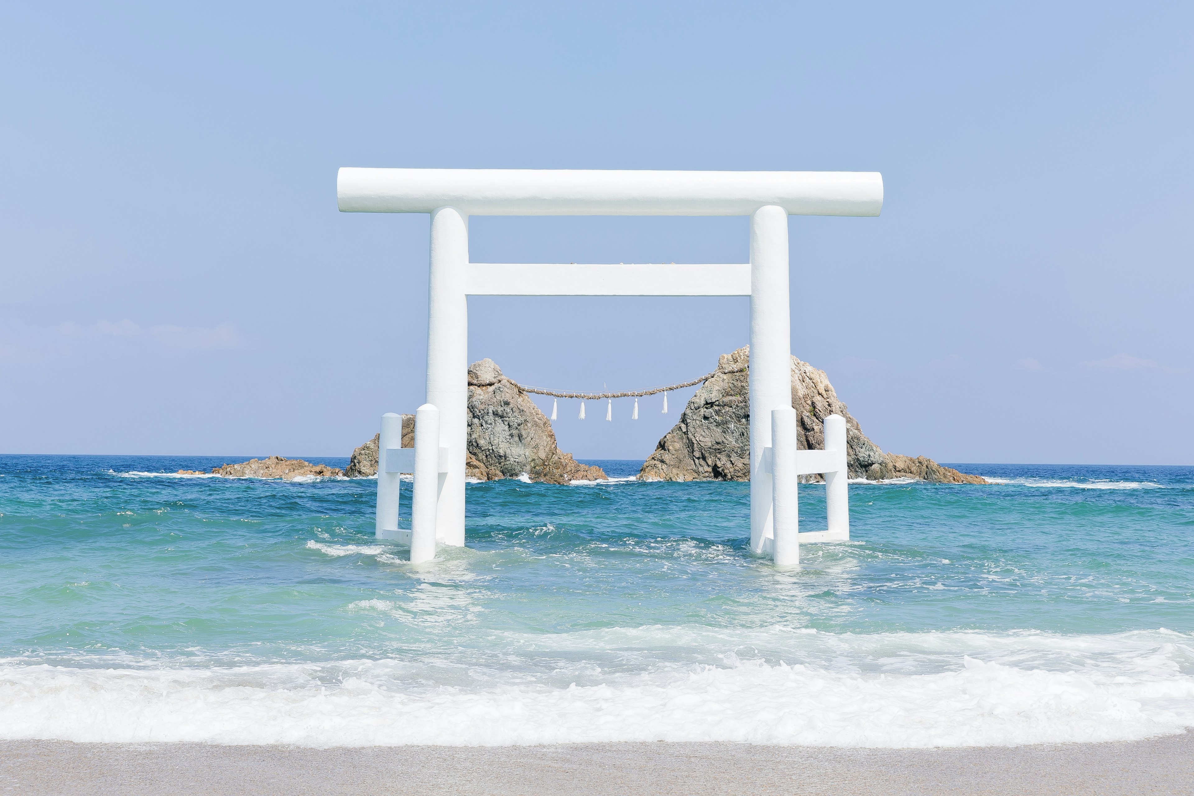 Puerta torii blanca de pie en el mar