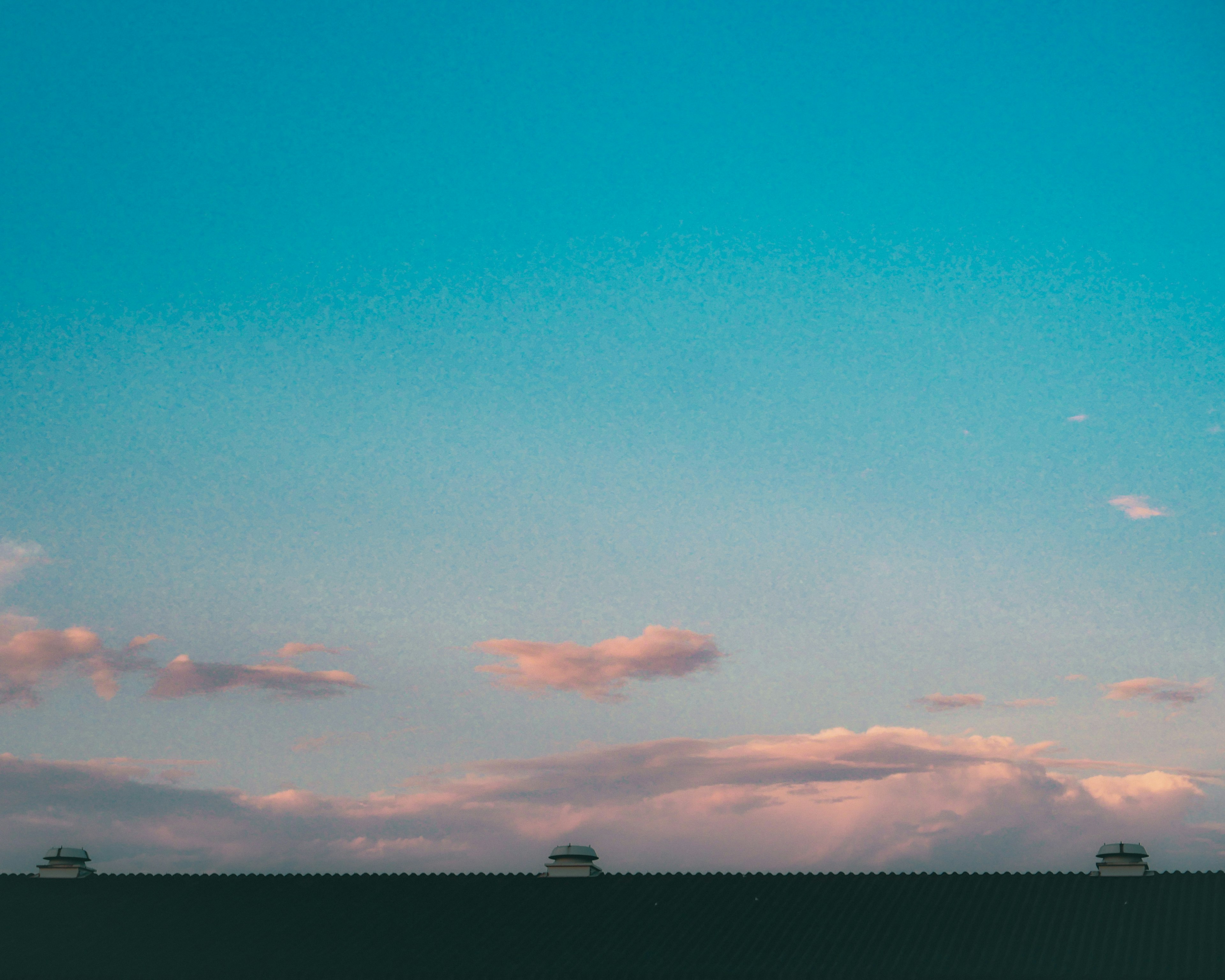 Un paesaggio con cielo blu e nuvole rosa con auto sulla strada