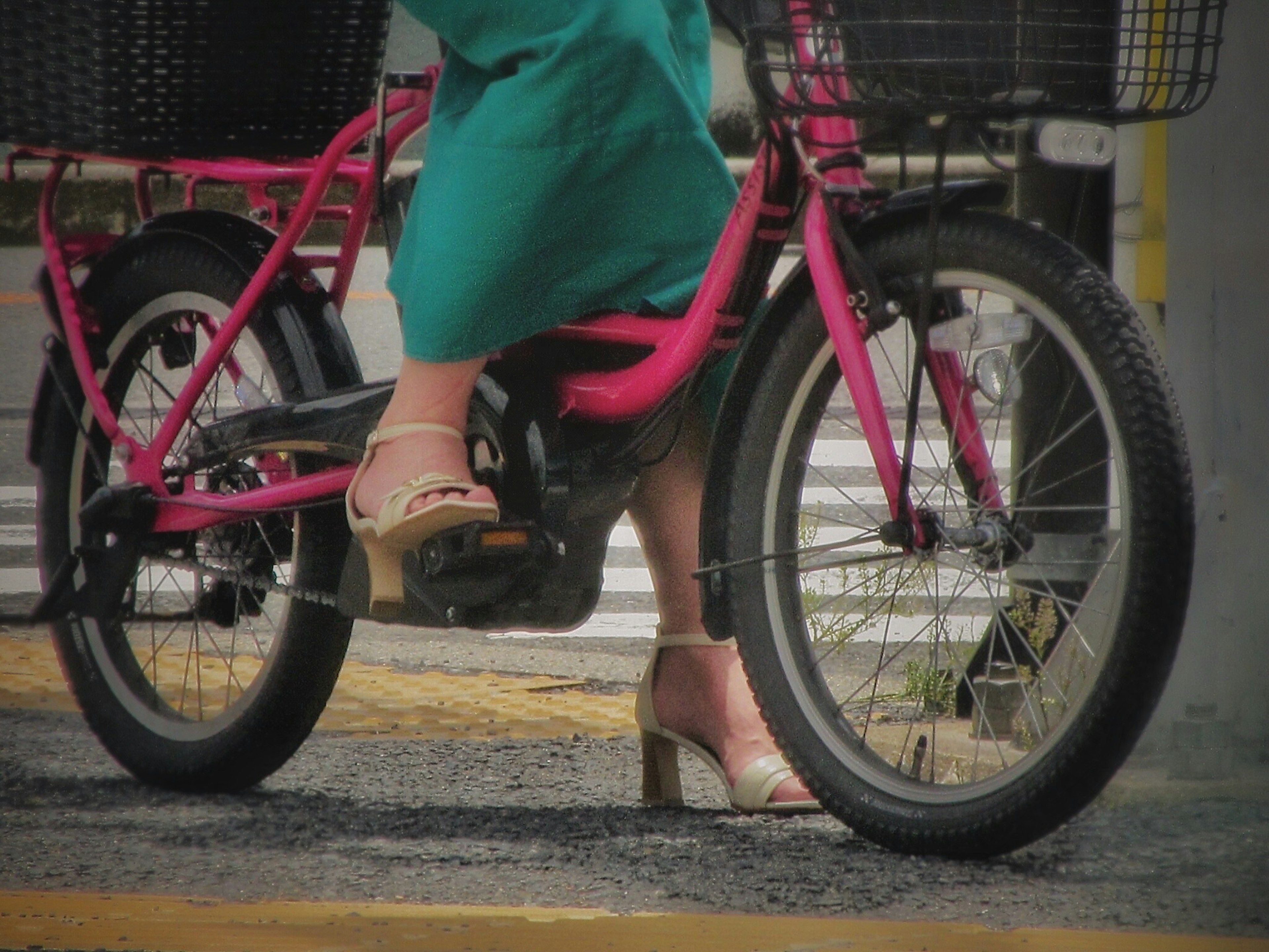 A woman's foot and skirt on a pink bicycle