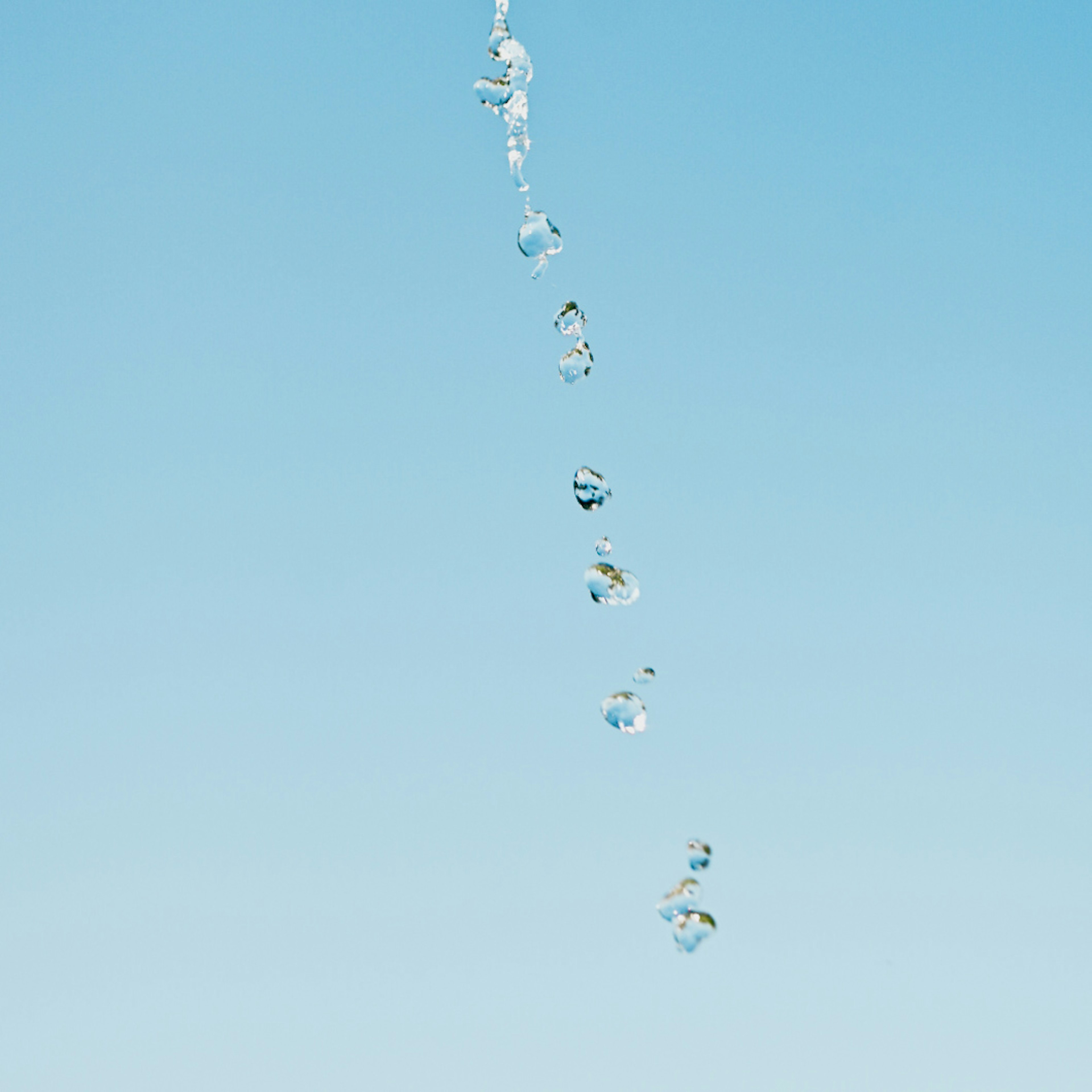 Water droplets falling against a clear blue sky