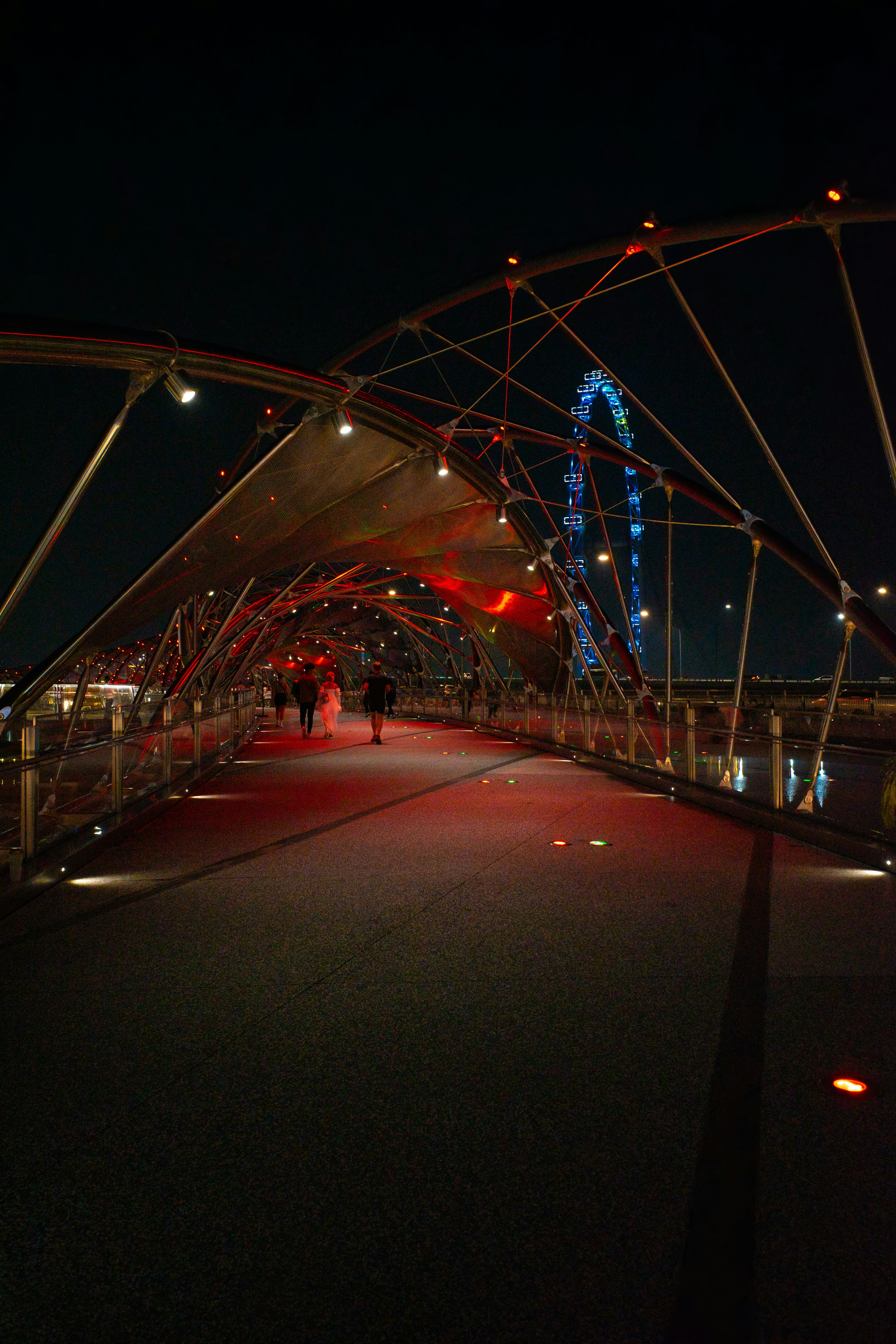 Pemandangan malam jembatan dengan pencahayaan merah dan roda Ferris di latar belakang