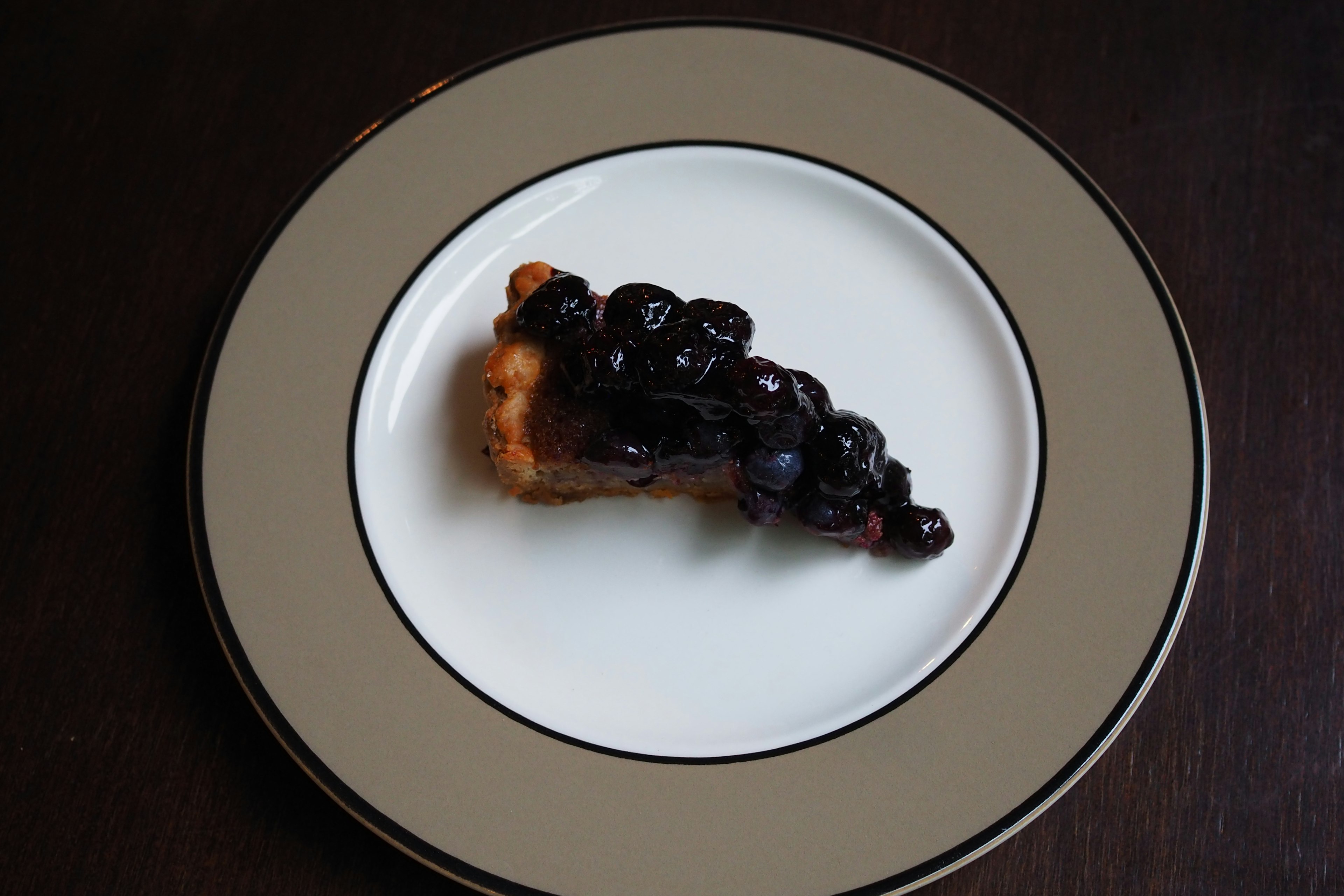 Slice of dessert topped with black berries on a white plate