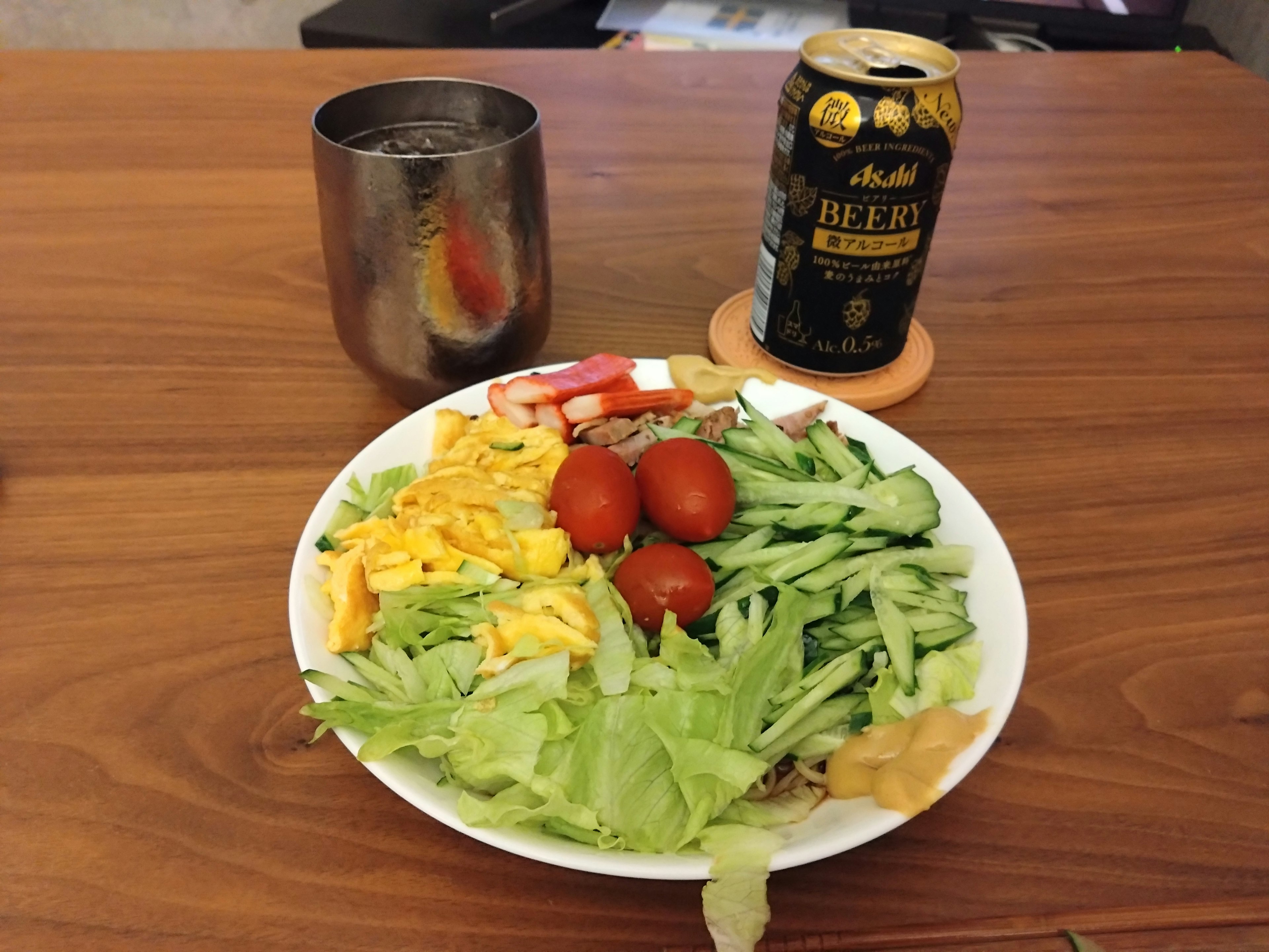 Un pasto con insalata di lattuga pomodori cetrioli e uova accanto a una lattina di birra