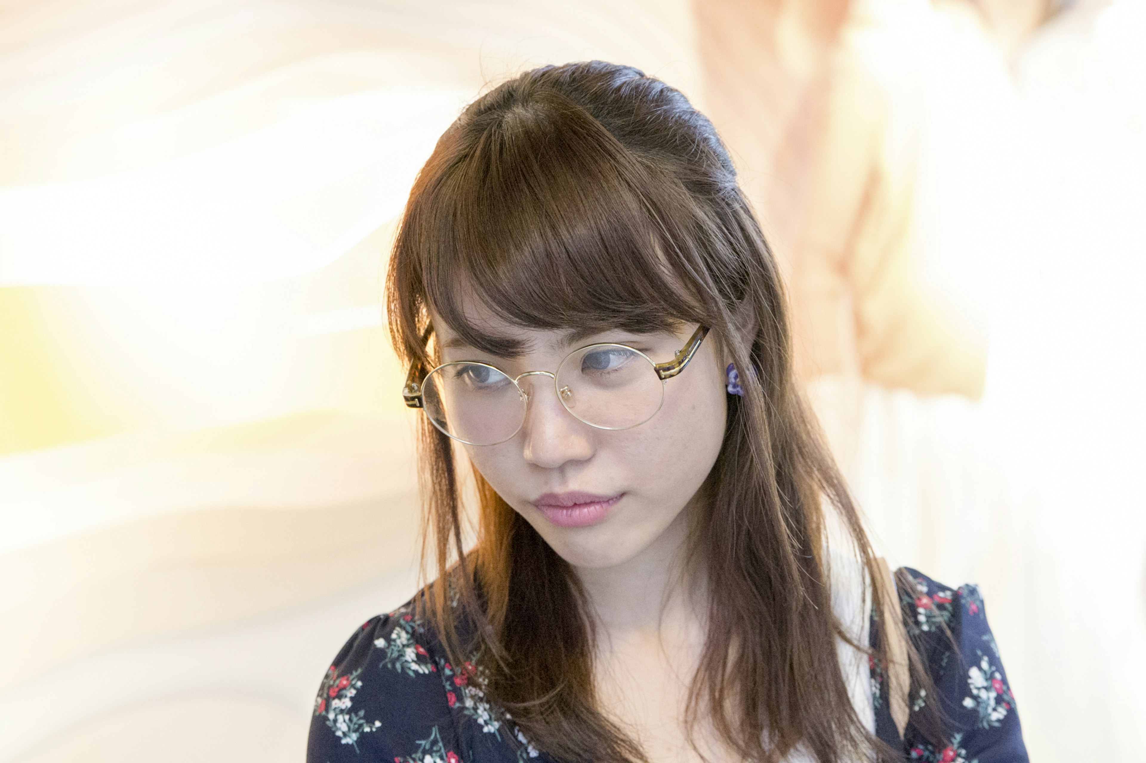 Retrato de una mujer con gafas vestida con ropa floral con fondo difuminado