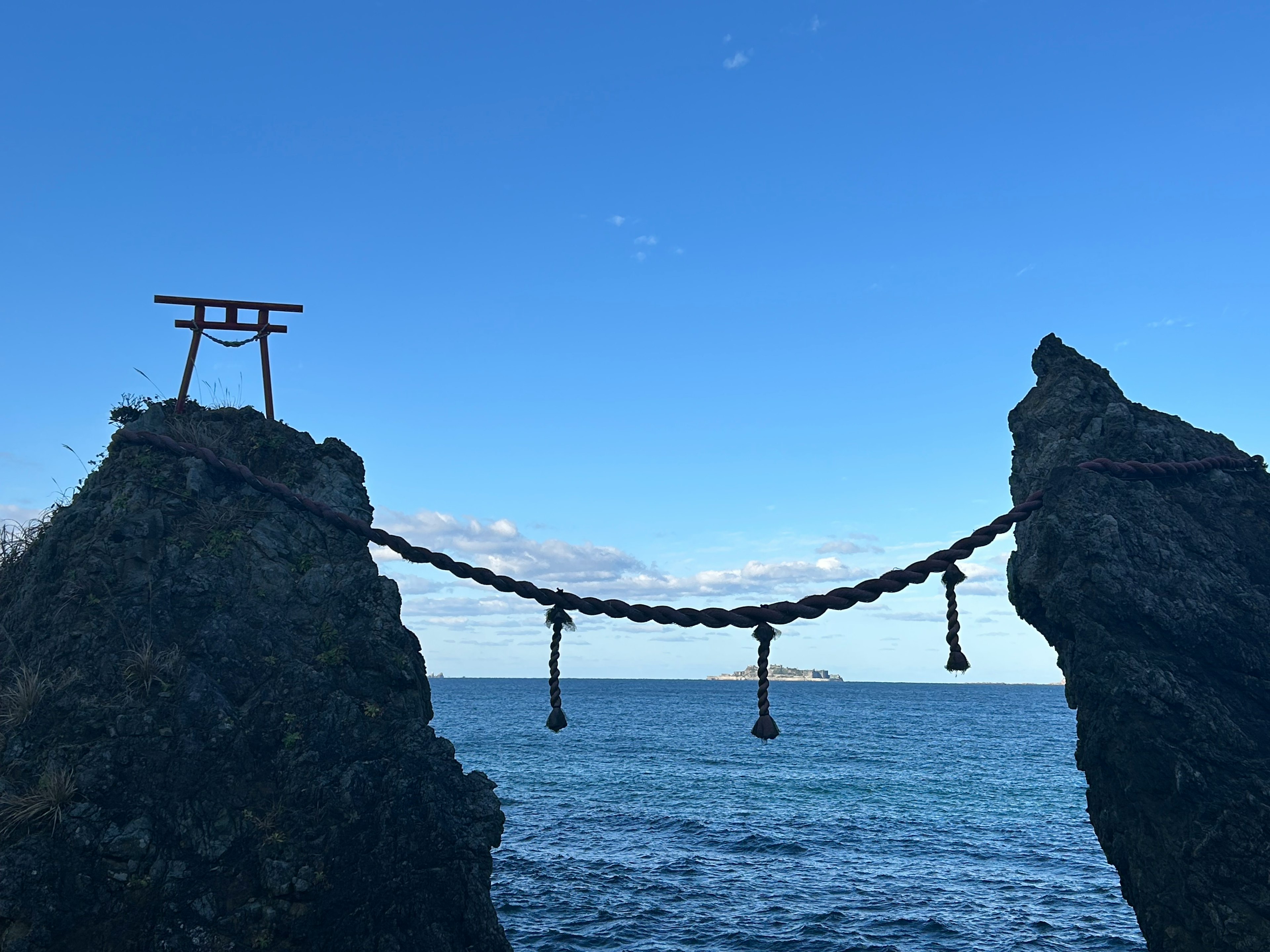 Puerta torii y puente de cadena entre rocas sobre el mar