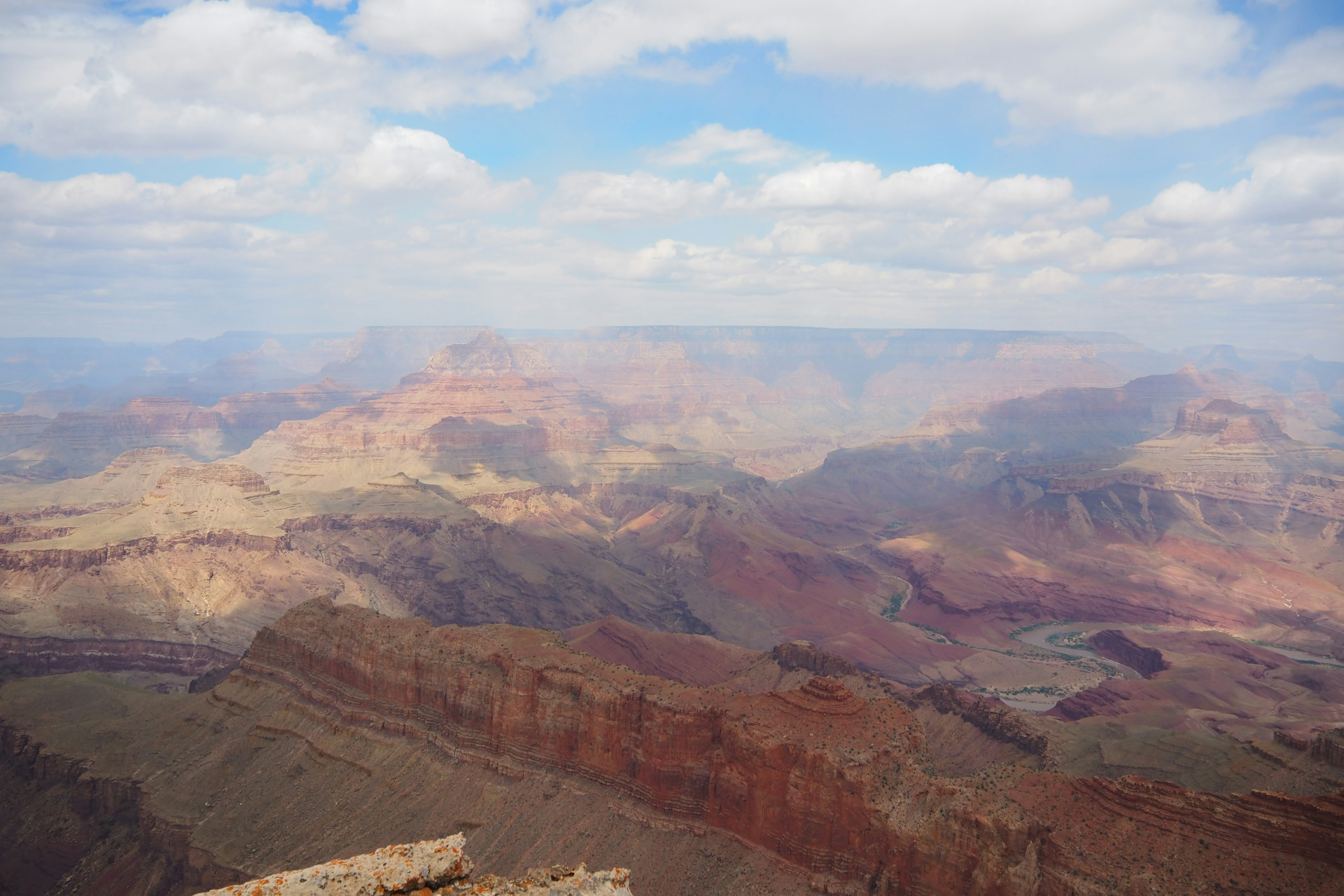 Cảnh quan rộng lớn của Grand Canyon với các lớp đá đầy màu sắc và mây trên bầu trời