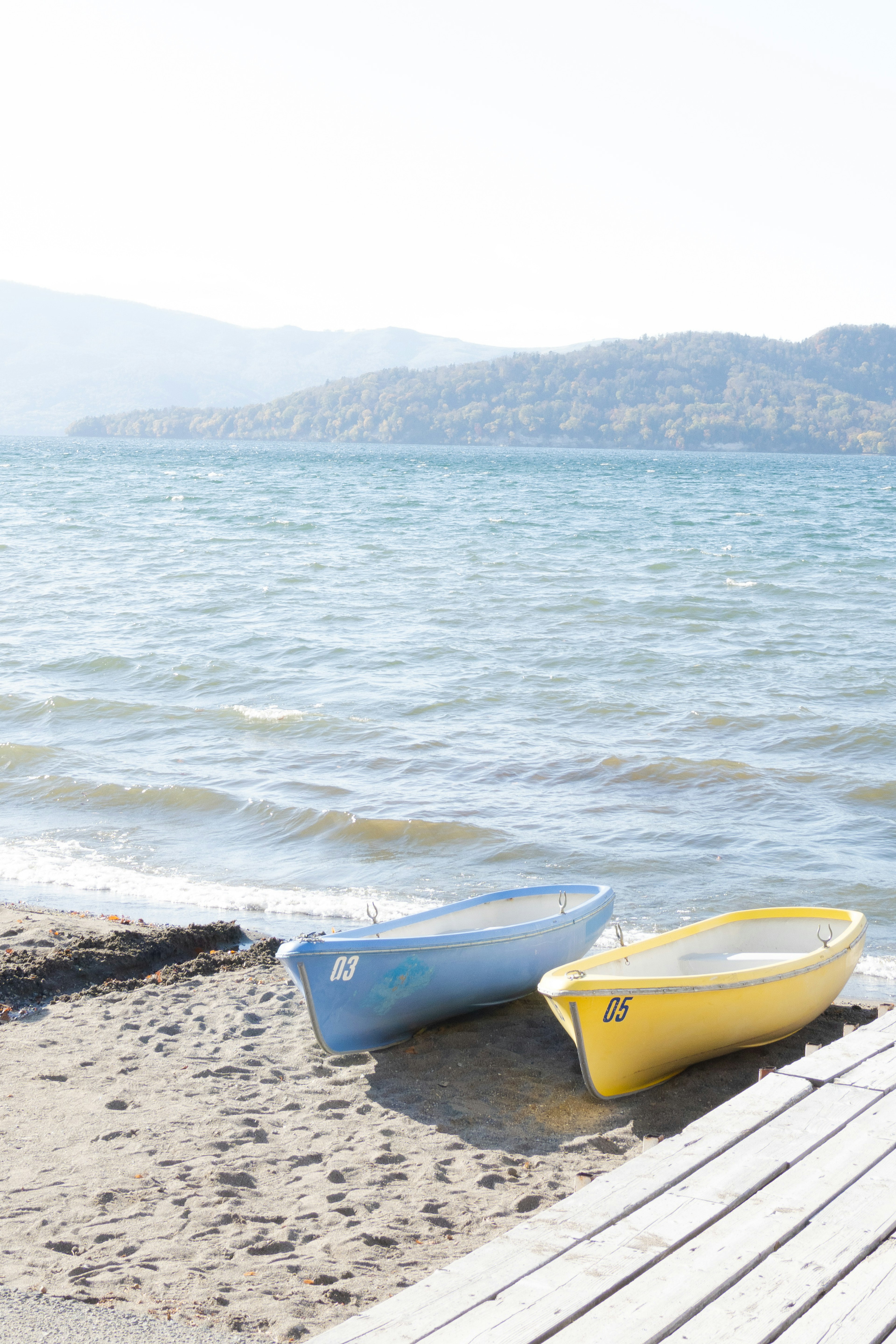 Botes azul y amarillo en una playa de arena junto al agua