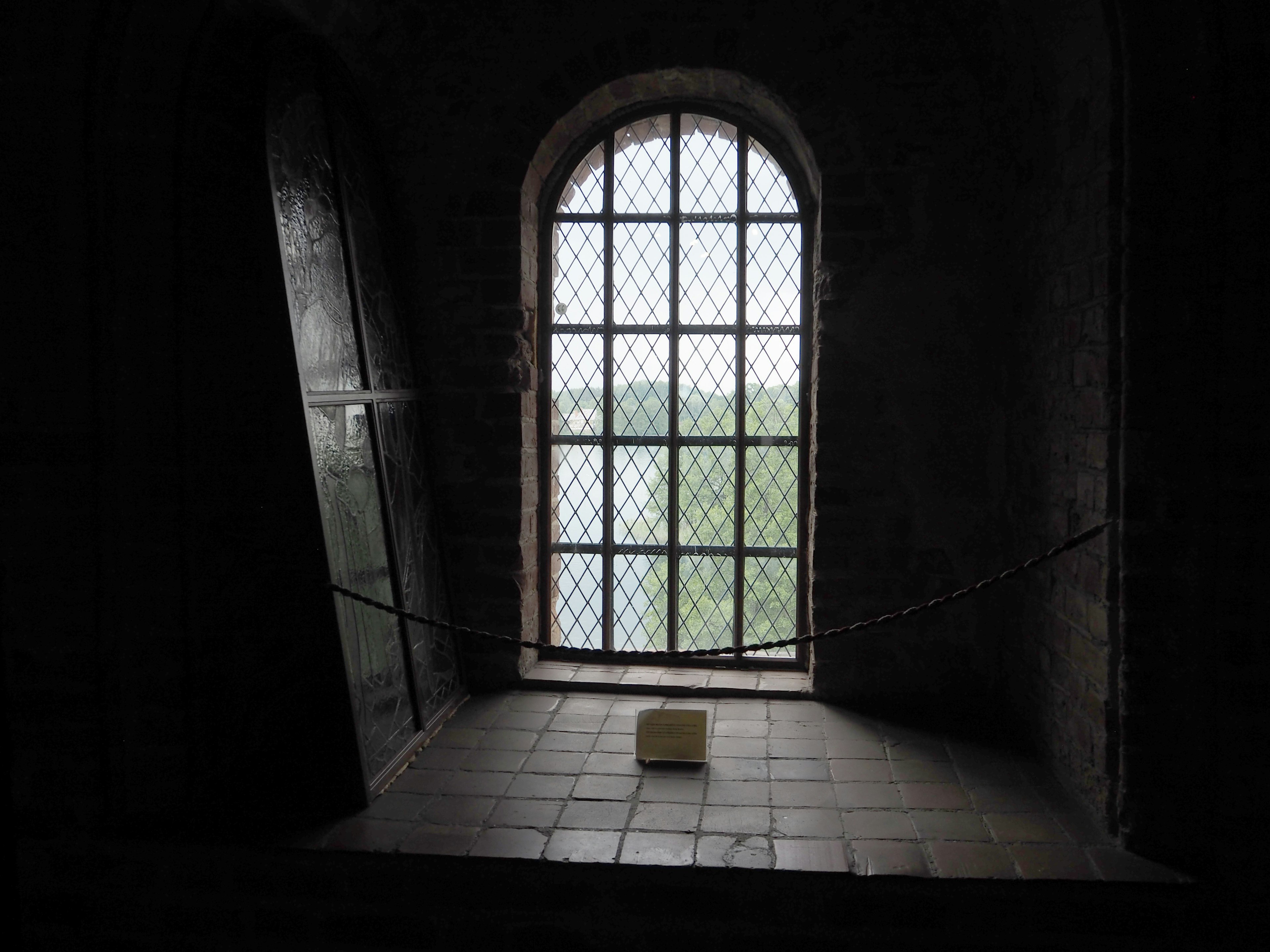 Ein schwach beleuchteter Raum mit einem Fenster, das Licht hereinlässt im Freien ist eine grüne Landschaft sichtbar