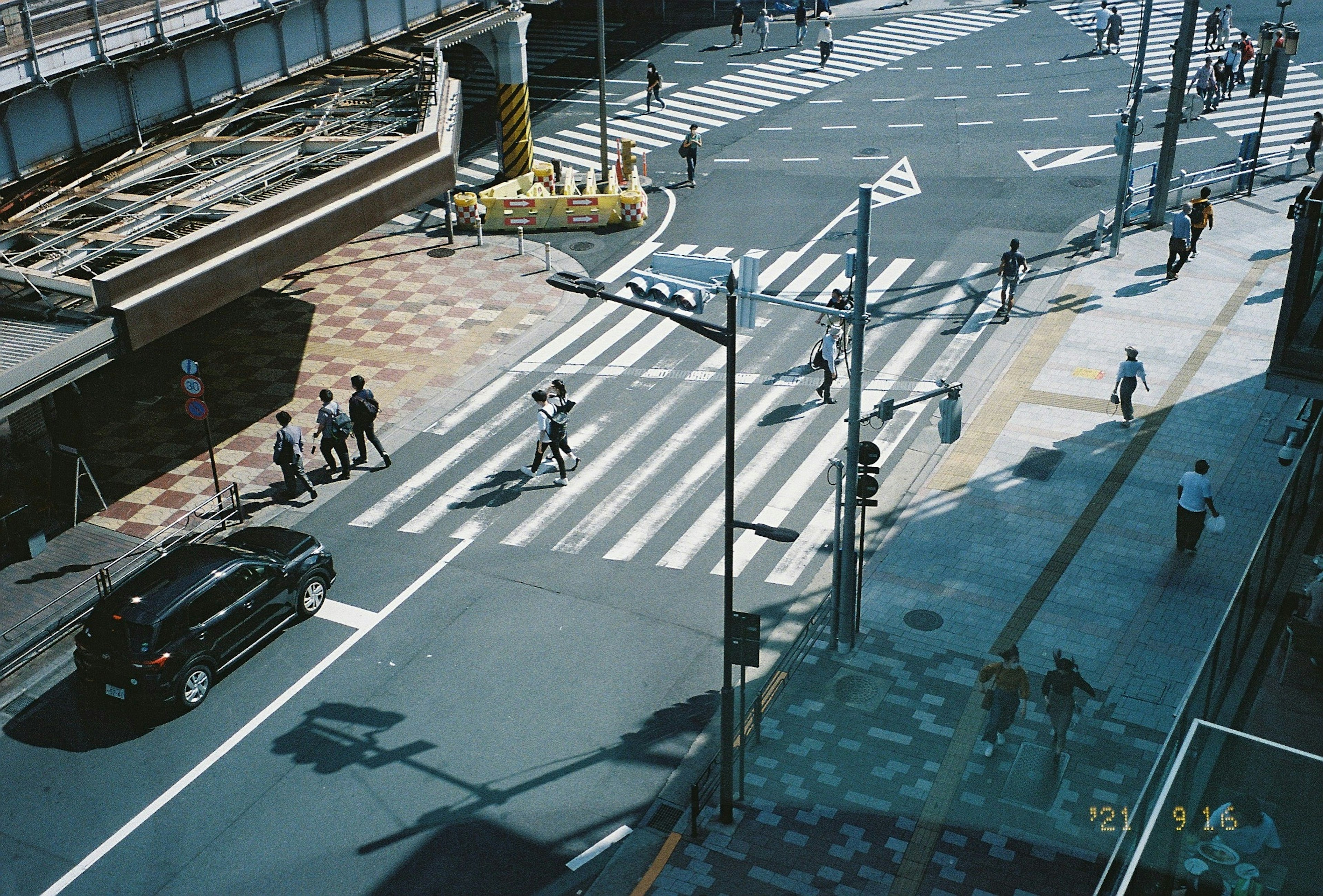 Aerial view of an intersection featuring pedestrians and cars crossing