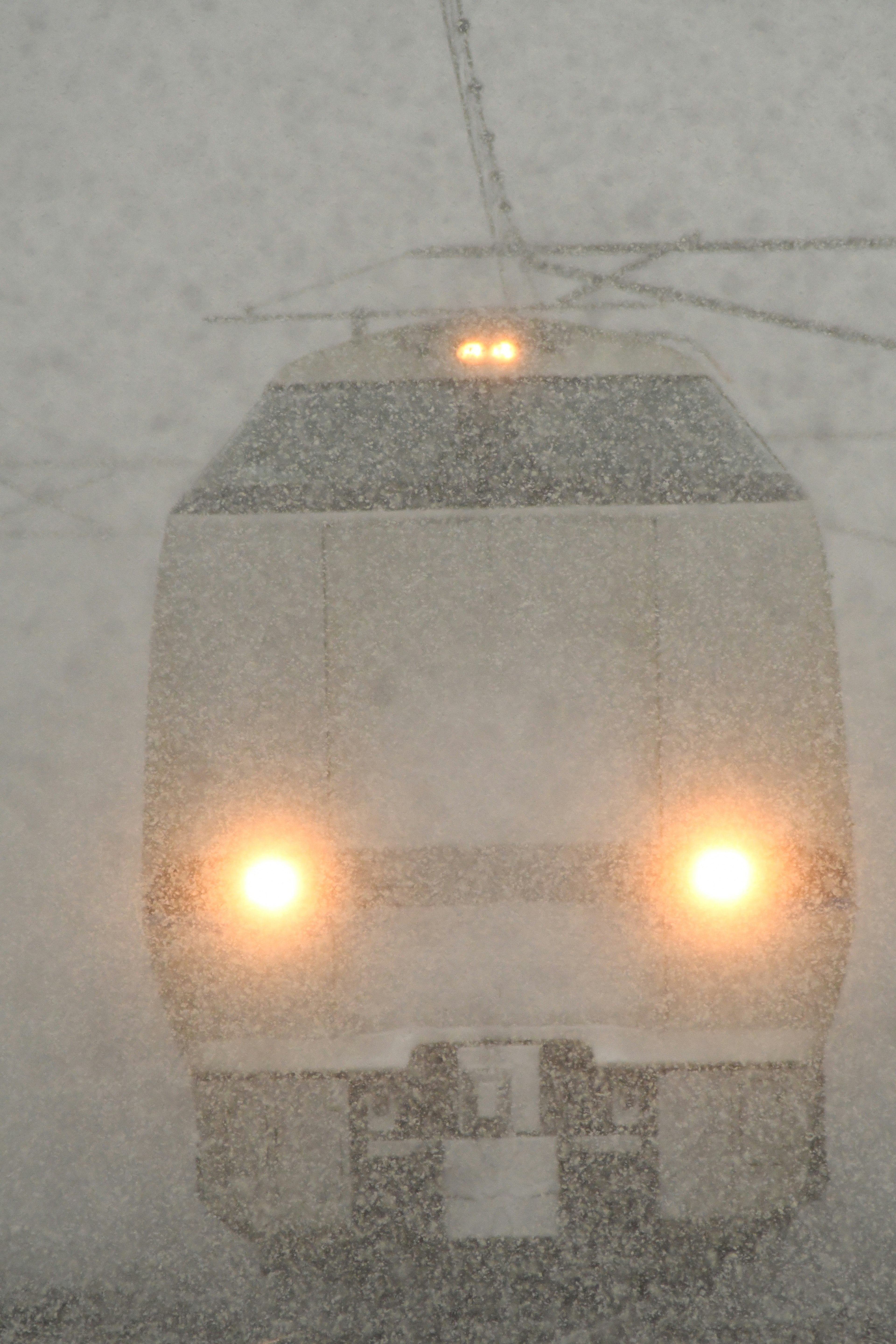 Train headlights visible in heavy snowstorm obscuring visibility