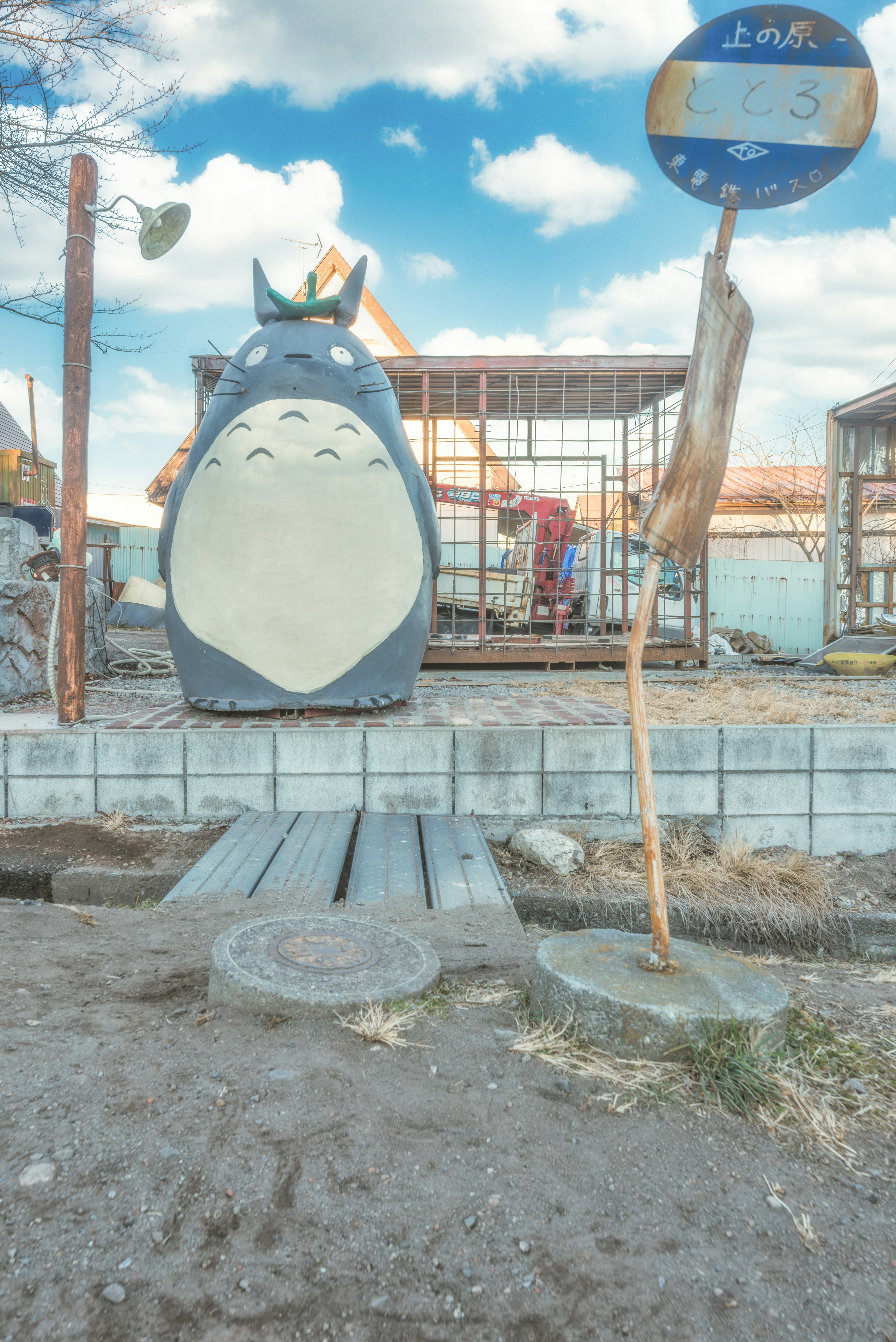 Cảnh quan với bức tượng Totoro và biển báo màu xanh