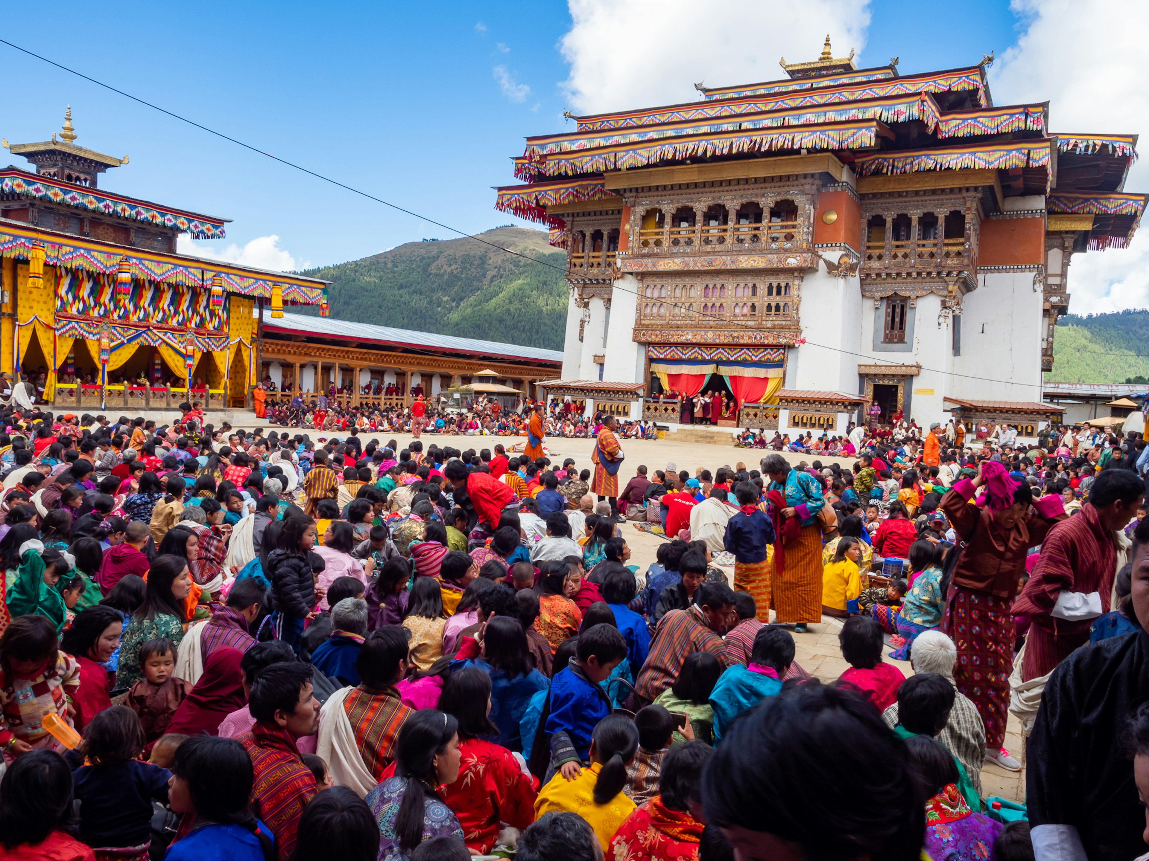 Kerumunan di festival tradisional di Bhutan dengan pakaian berwarna-warni dan arsitektur