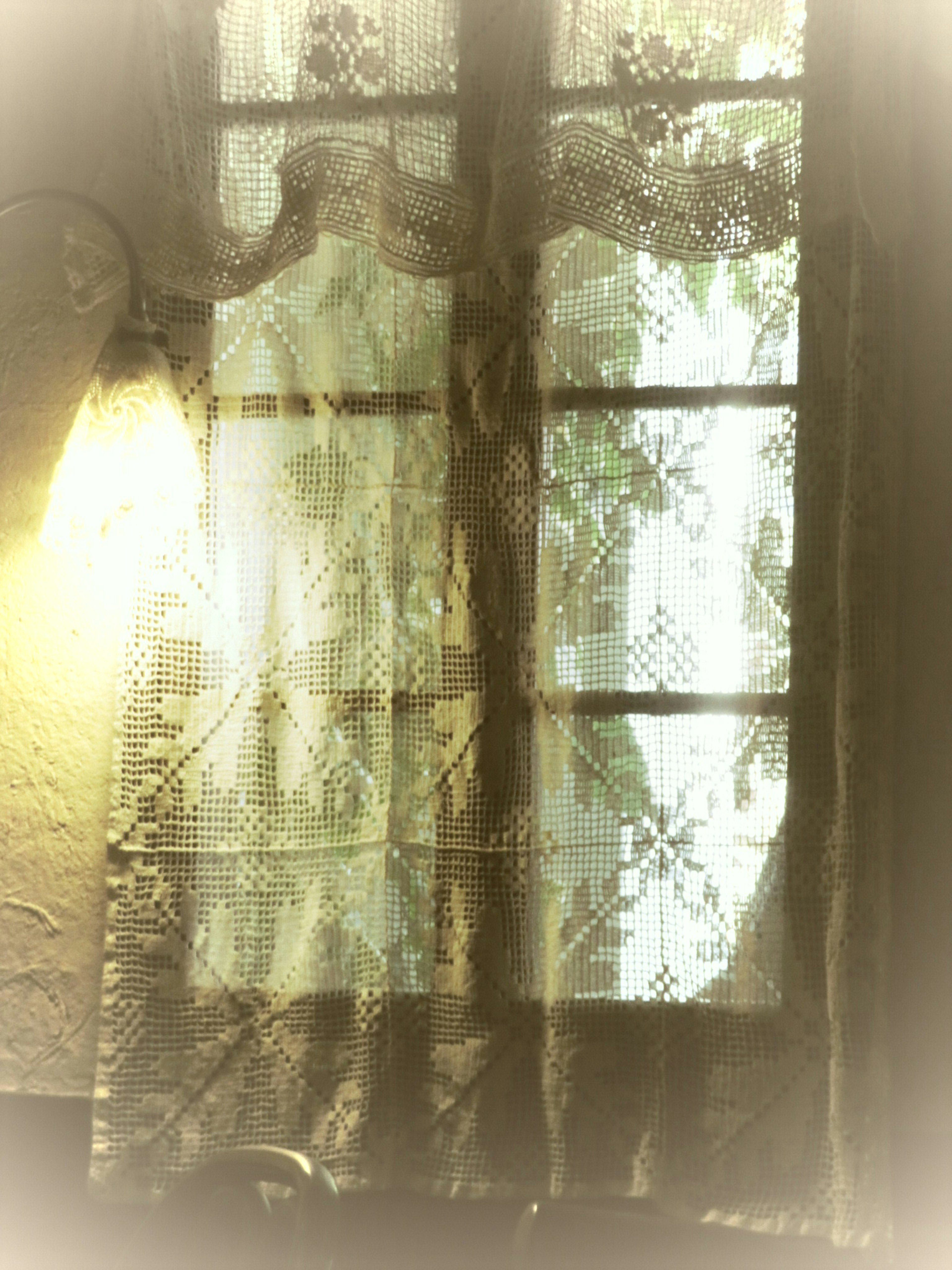 Soft light and shadow patterns through lace curtains at a window