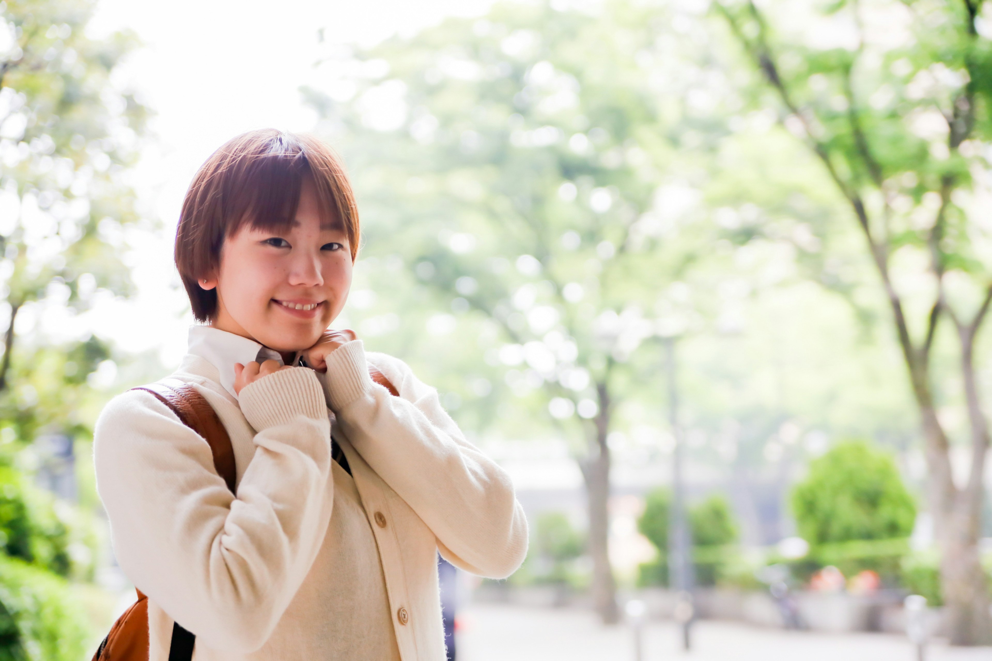 A smiling woman in a park with a bright green background