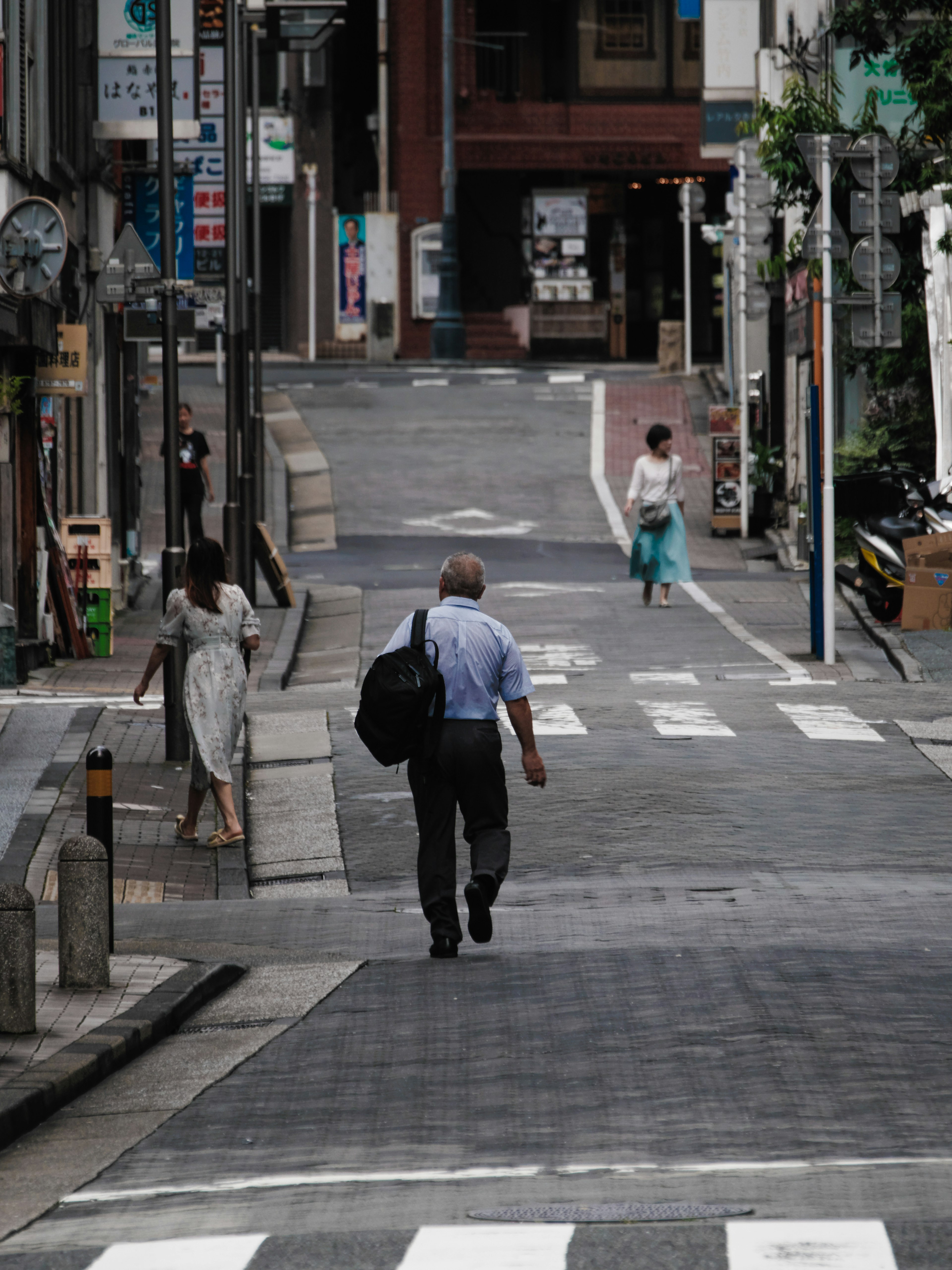 Un uomo che cammina lungo una strada tranquilla con due donne nelle vicinanze