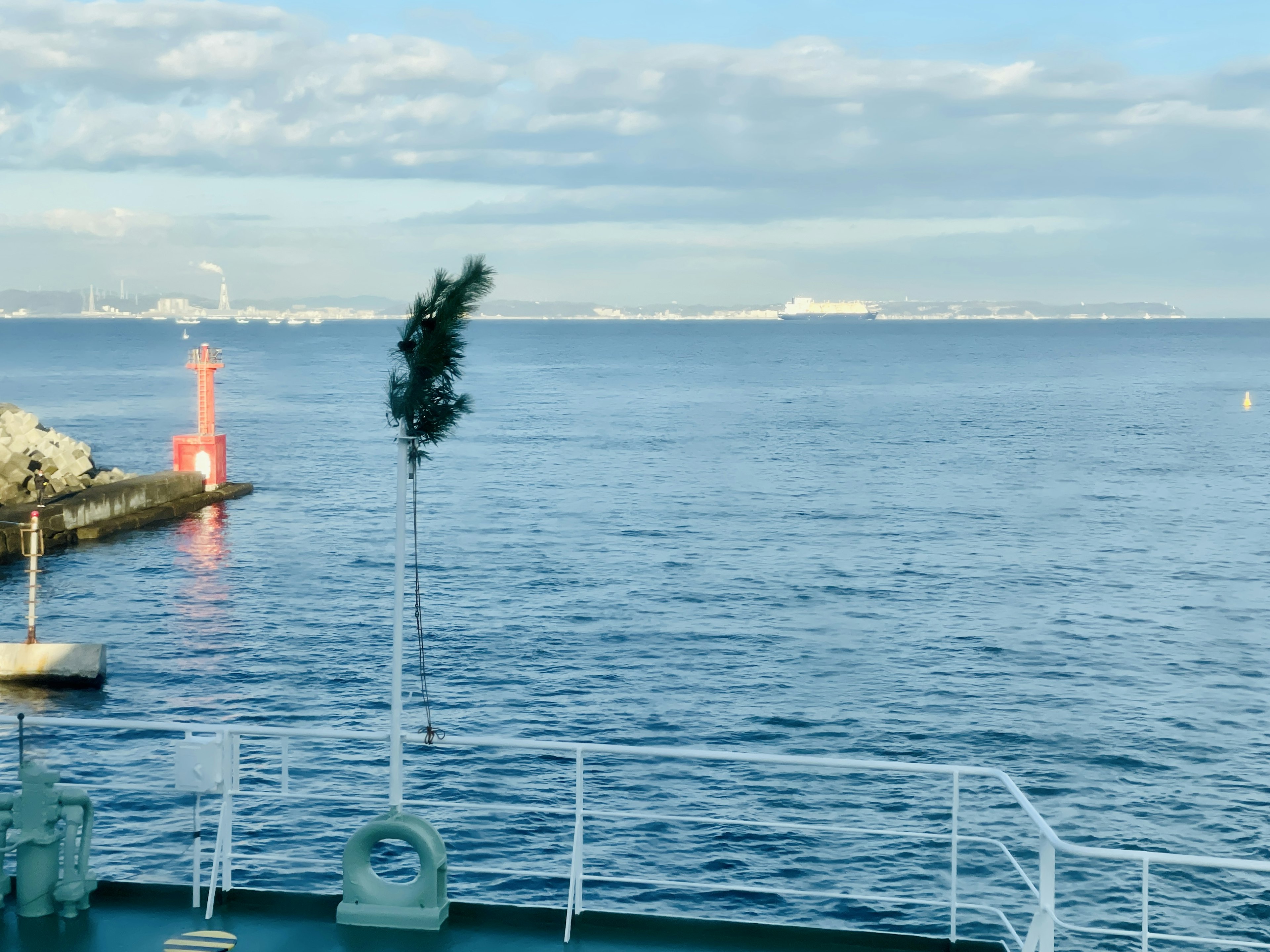 Malersicher Blick auf den blauen Ozean und den Himmel mit einem roten Leuchtturm im Hafen