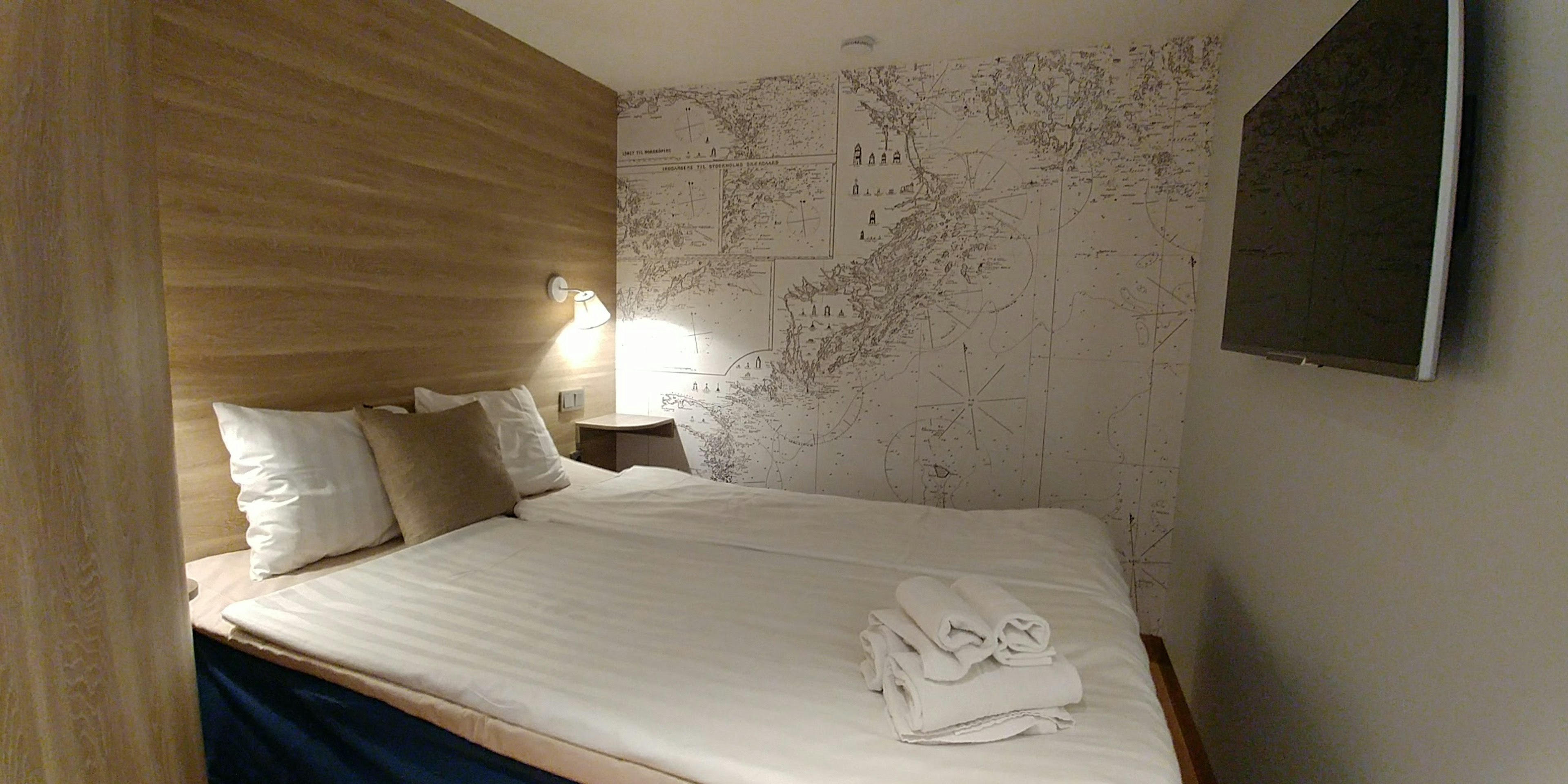 Intérieur de chambre moderne et confortable avec murs en bois papier peint à motif de carte serviettes sur le lit