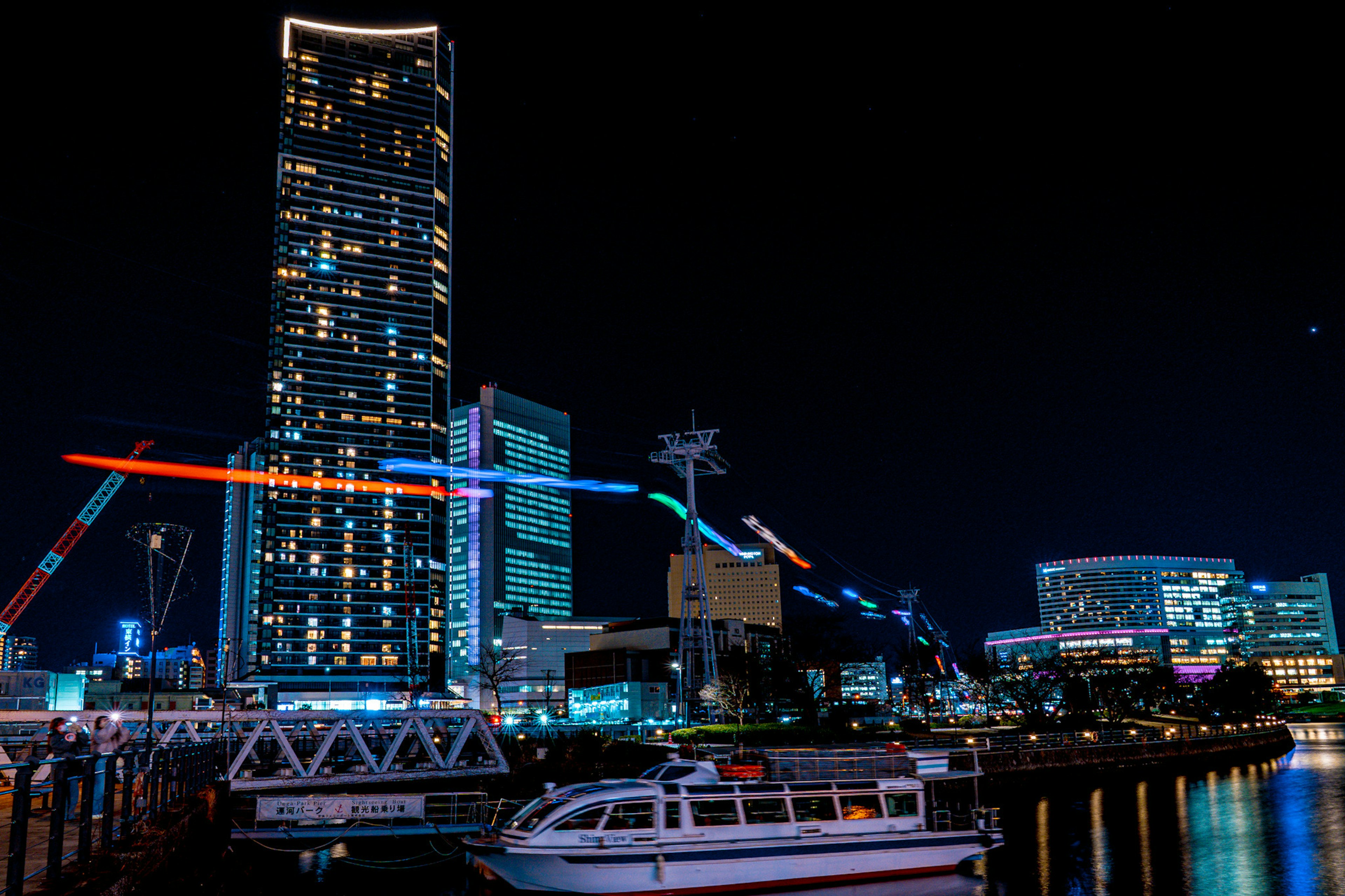 Hermosa vista nocturna del puerto de Yokohama con rascacielos y un barco con luces coloridas