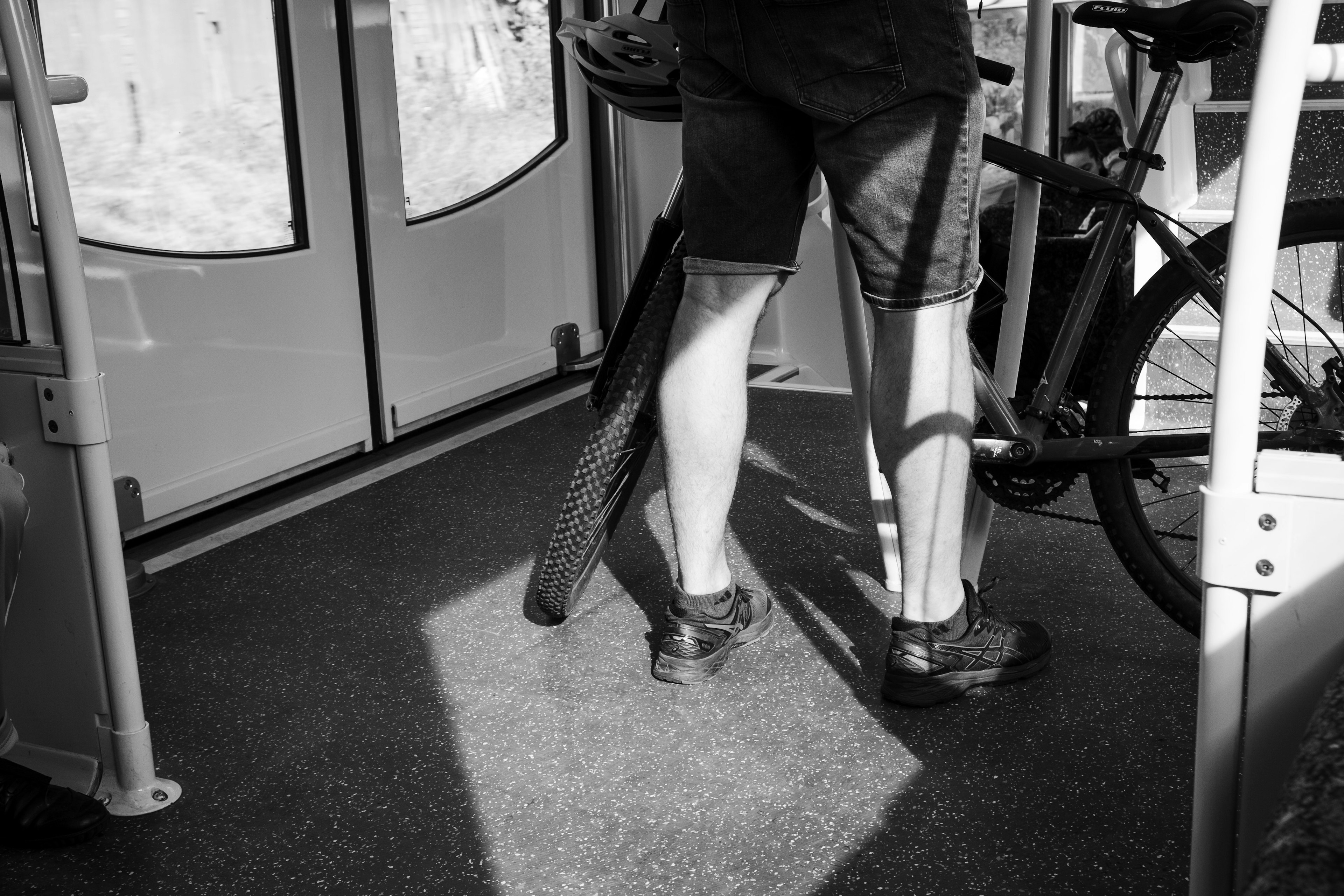 A person standing in public transport holding a bicycle