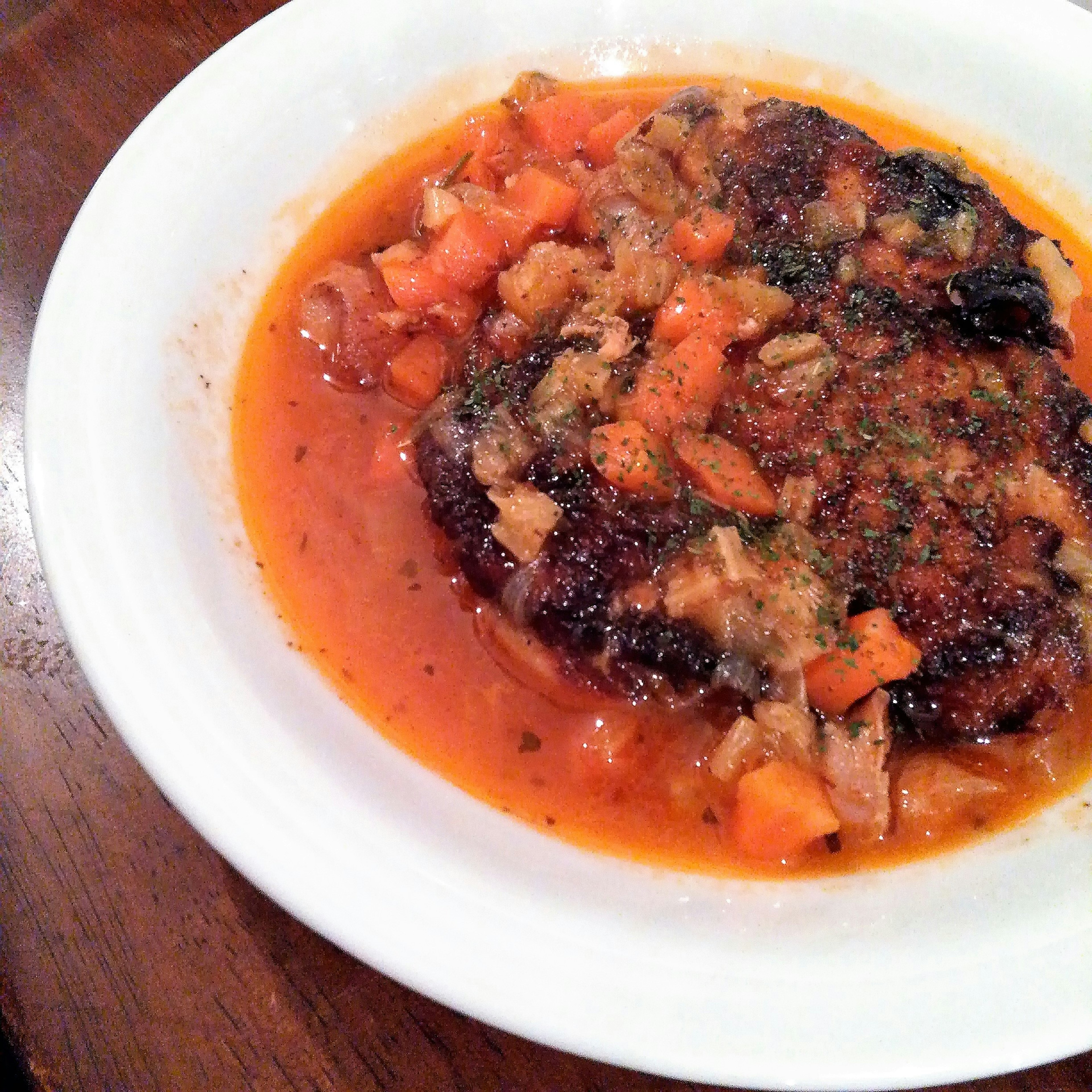 Plate of meat dish topped with tomato sauce and vegetables