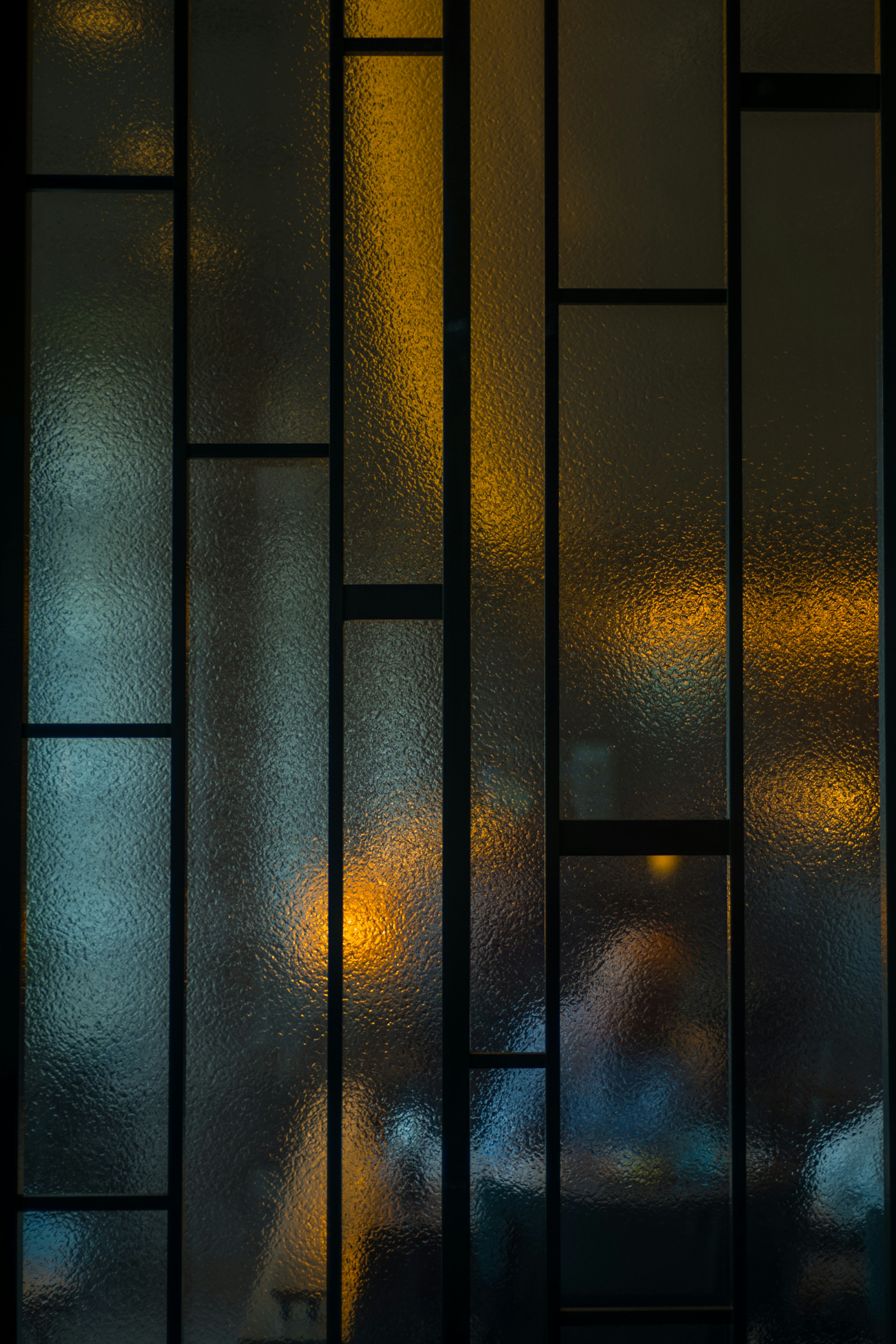 Frosted glass panels reflecting warm light and silhouettes of people