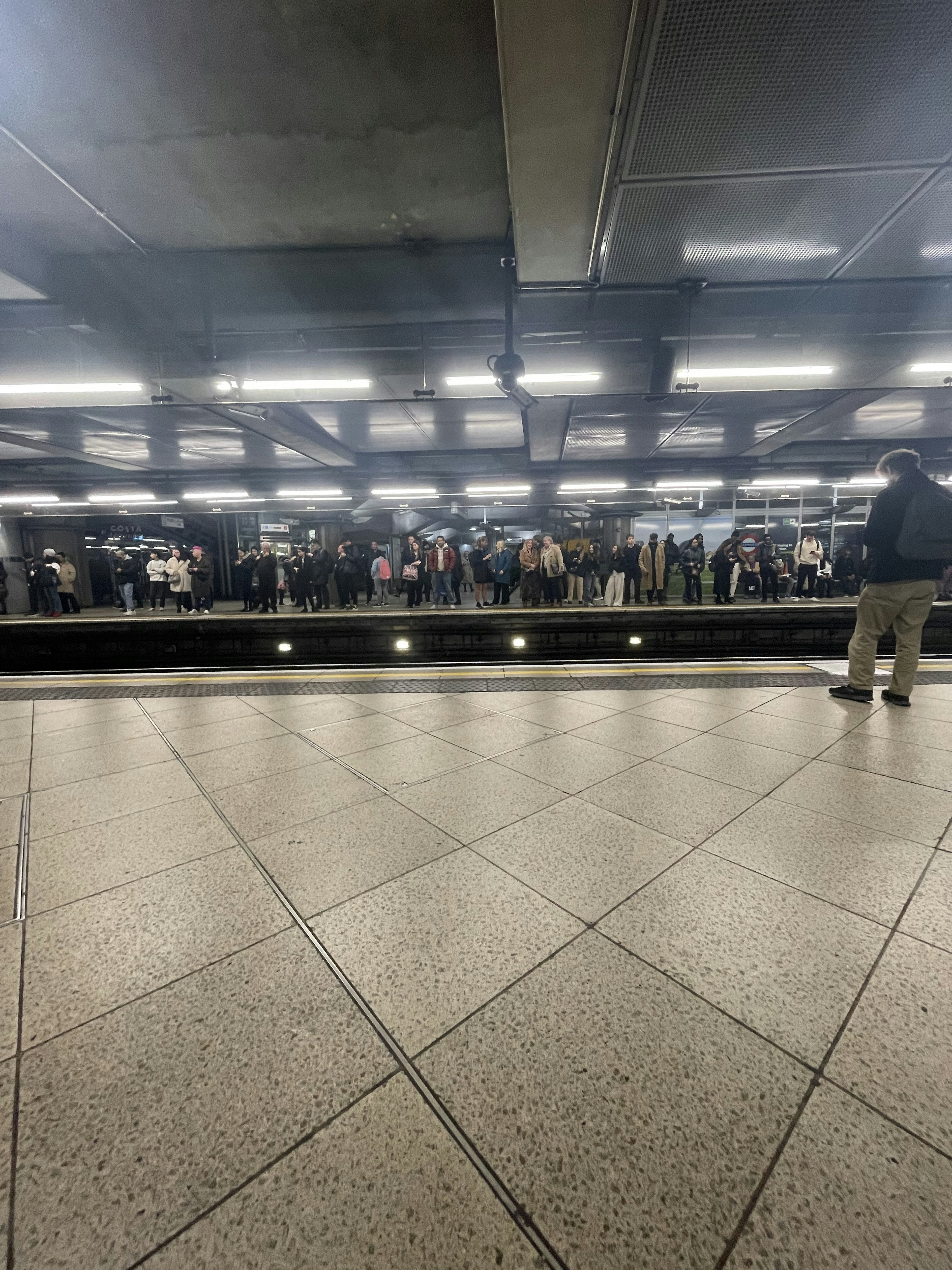 Folla di persone su una banchina della metropolitana con luci riflesse