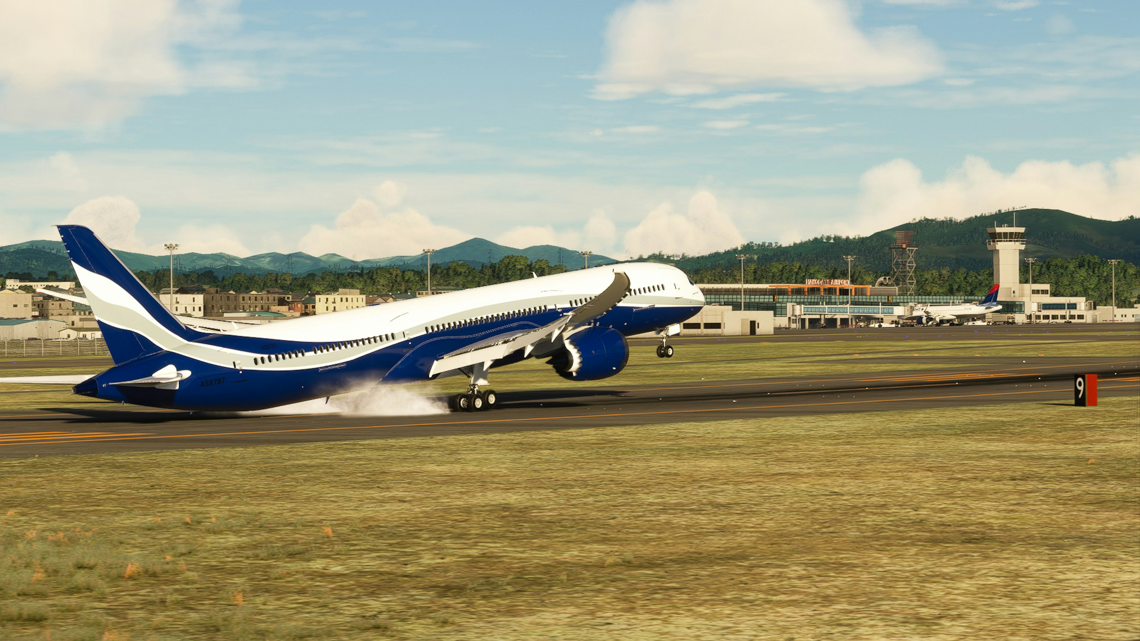 Blue and white aircraft taking off on the runway with mountains and airport in the background