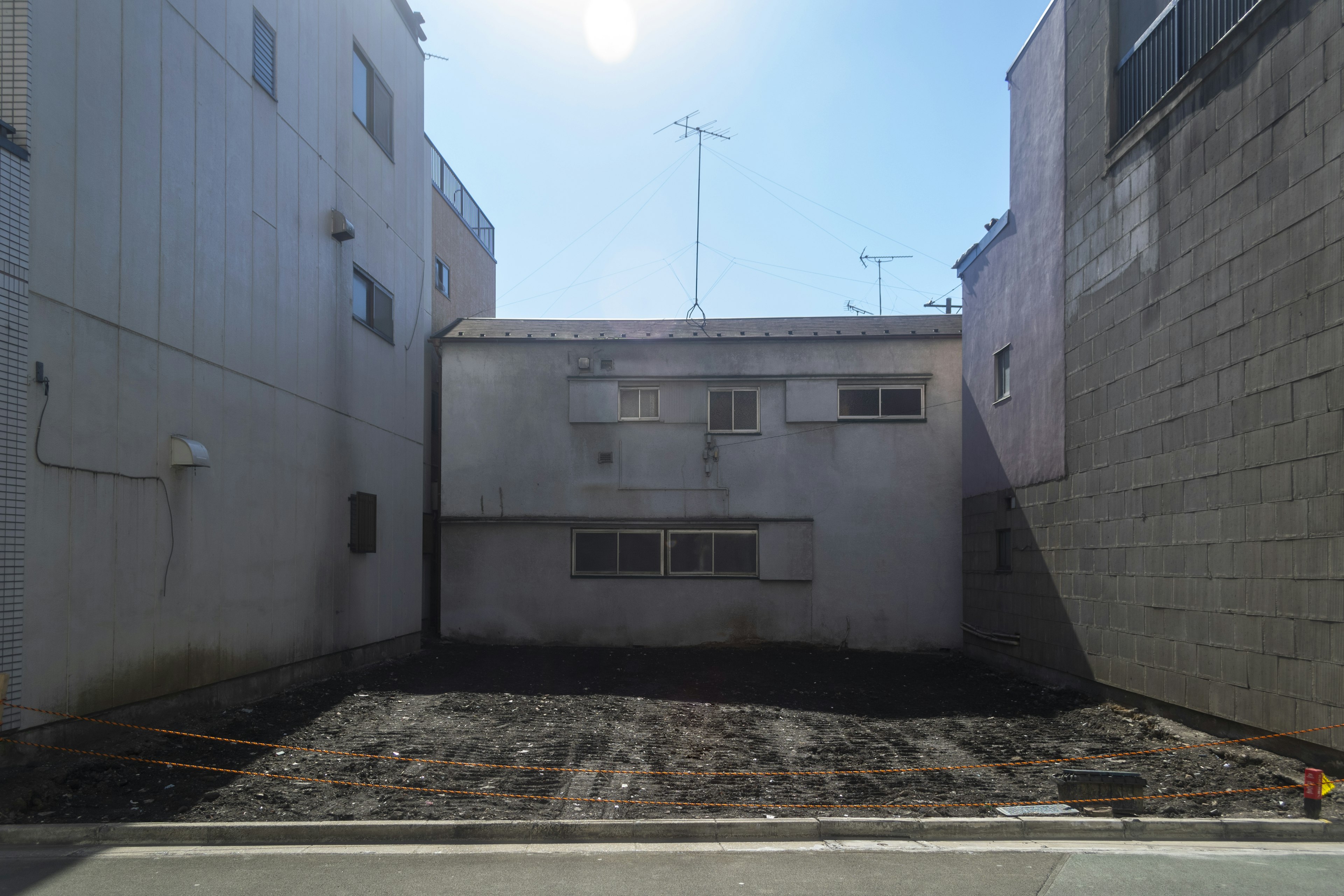 Vista posteriore di un edificio che affaccia su un terreno vuoto e cielo azzurro