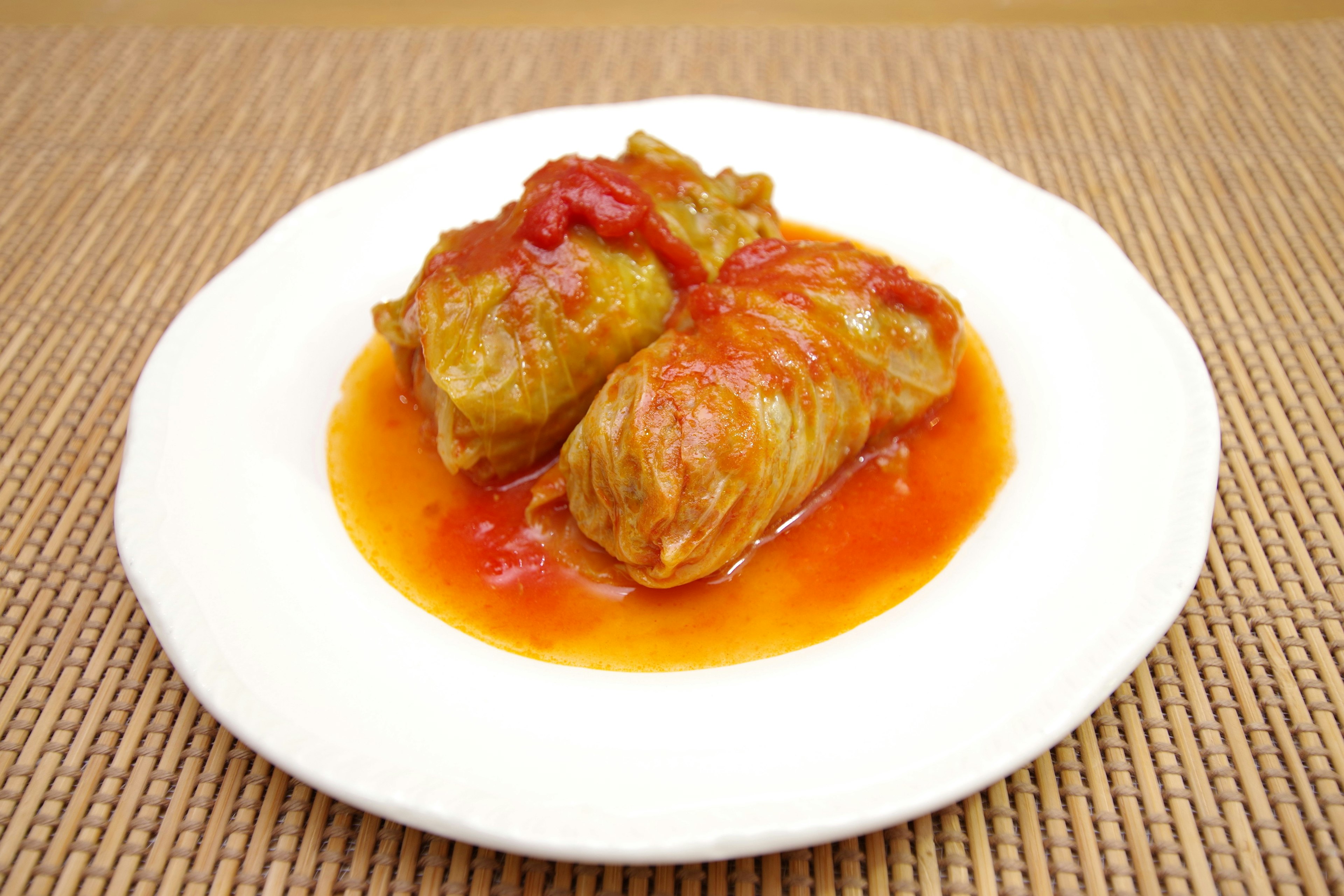 Rouleaux de chou garnis de sauce tomate sur une assiette blanche