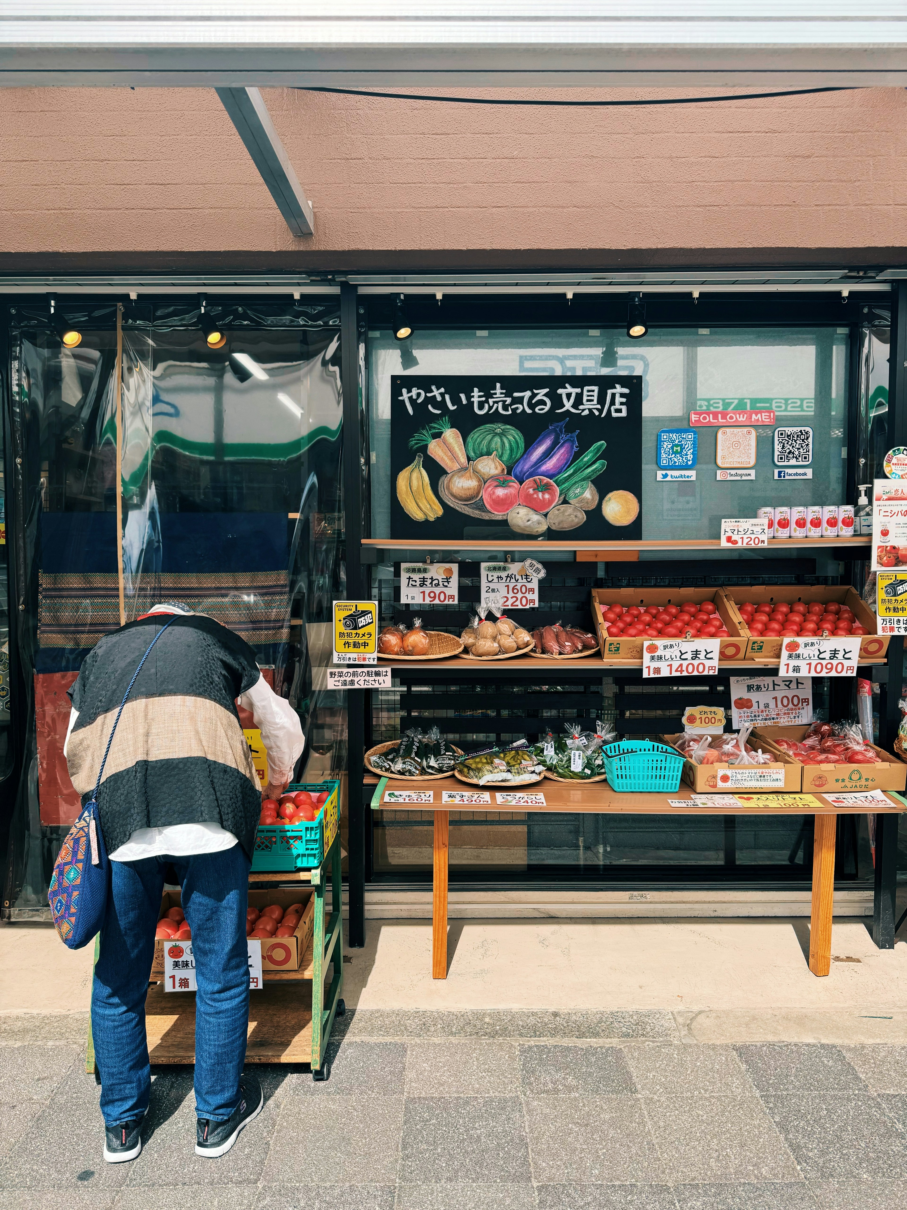 新鮮な野菜と果物が並ぶ市場の店外で買い物をする女性