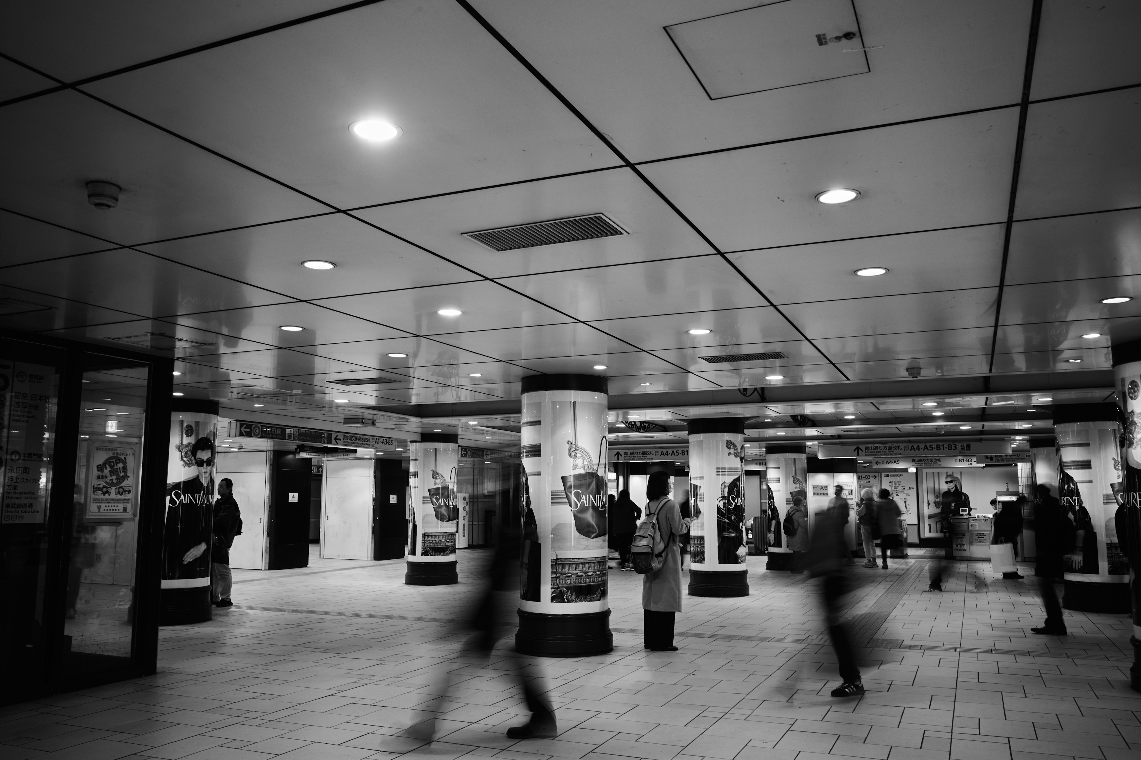 Escena de una estación de metro concurrida con personas caminando en blanco y negro