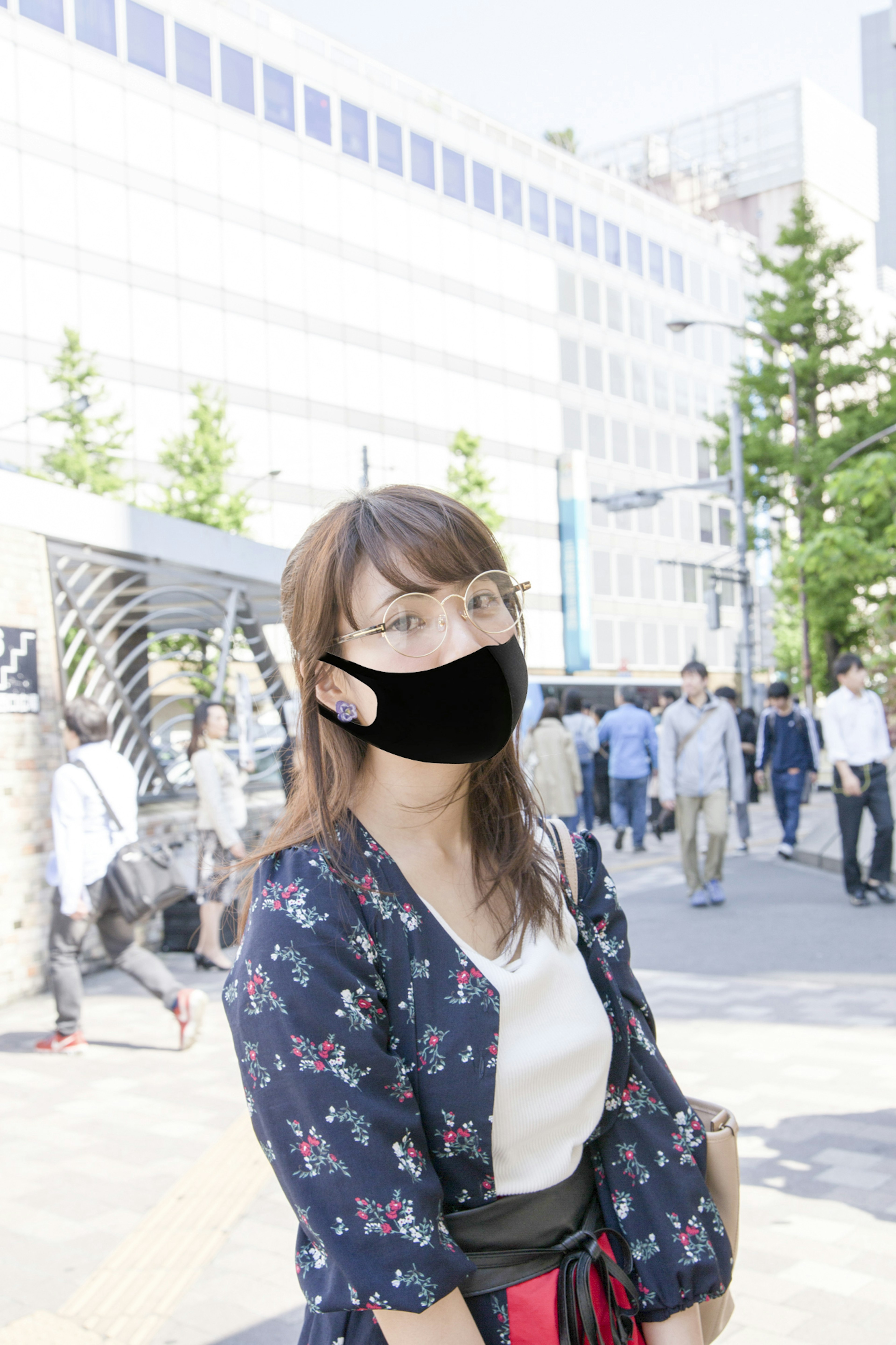 Woman wearing a black mask and floral jacket in a city street scene